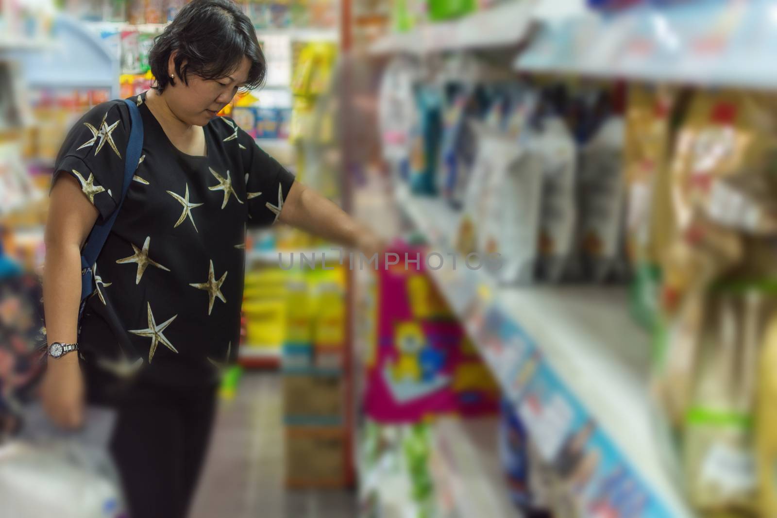 Customer woman shopping by selecting a variety accessories or pet food from pet goods shelf in petshop for her dog open daily for service everyday.