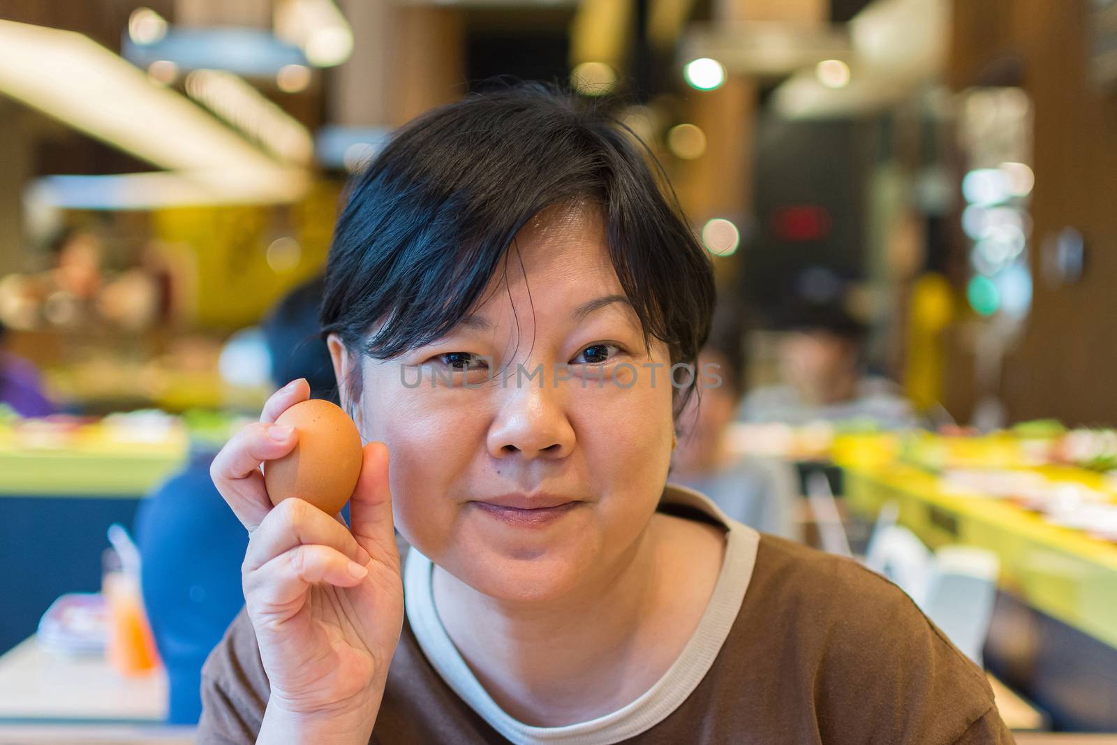 Asia woman plump body holding a egg, defocus blurred on BBQ. yakiniku grill buffet restaurant background.