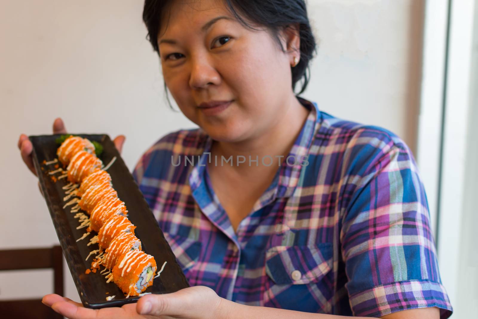 Asia woman plump body holding california roll on dish in japanese food buffet restaurant.