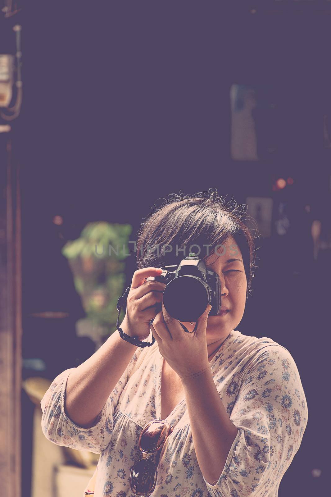 Asia woman plump body in colorful dress take a photo by her camera at old town when travel , process in vintage style