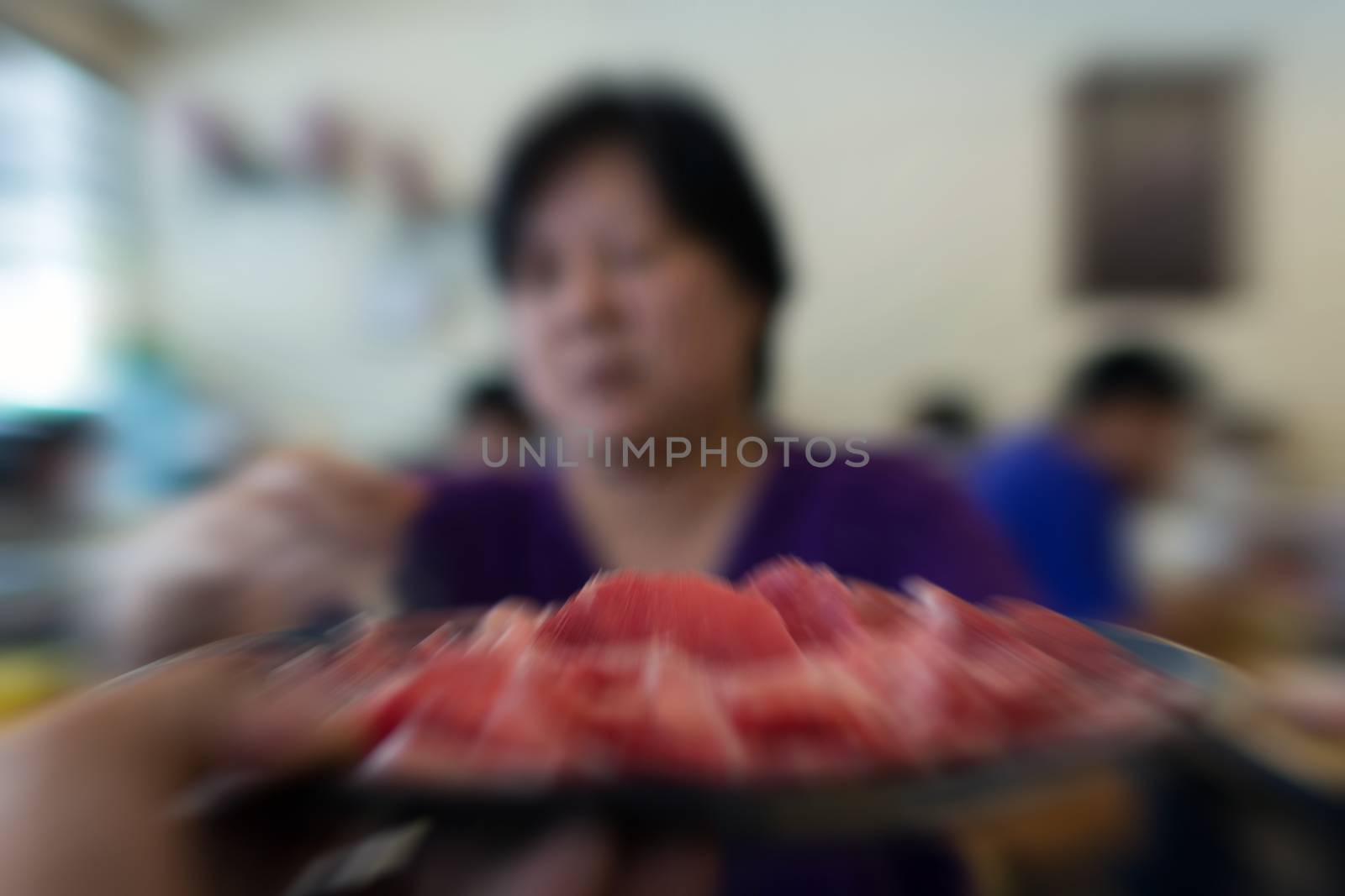 Blurred zoom of Asia woman plump body cooking food by put a flesh beef in to a hot pot for make a sukiyaki or shabu