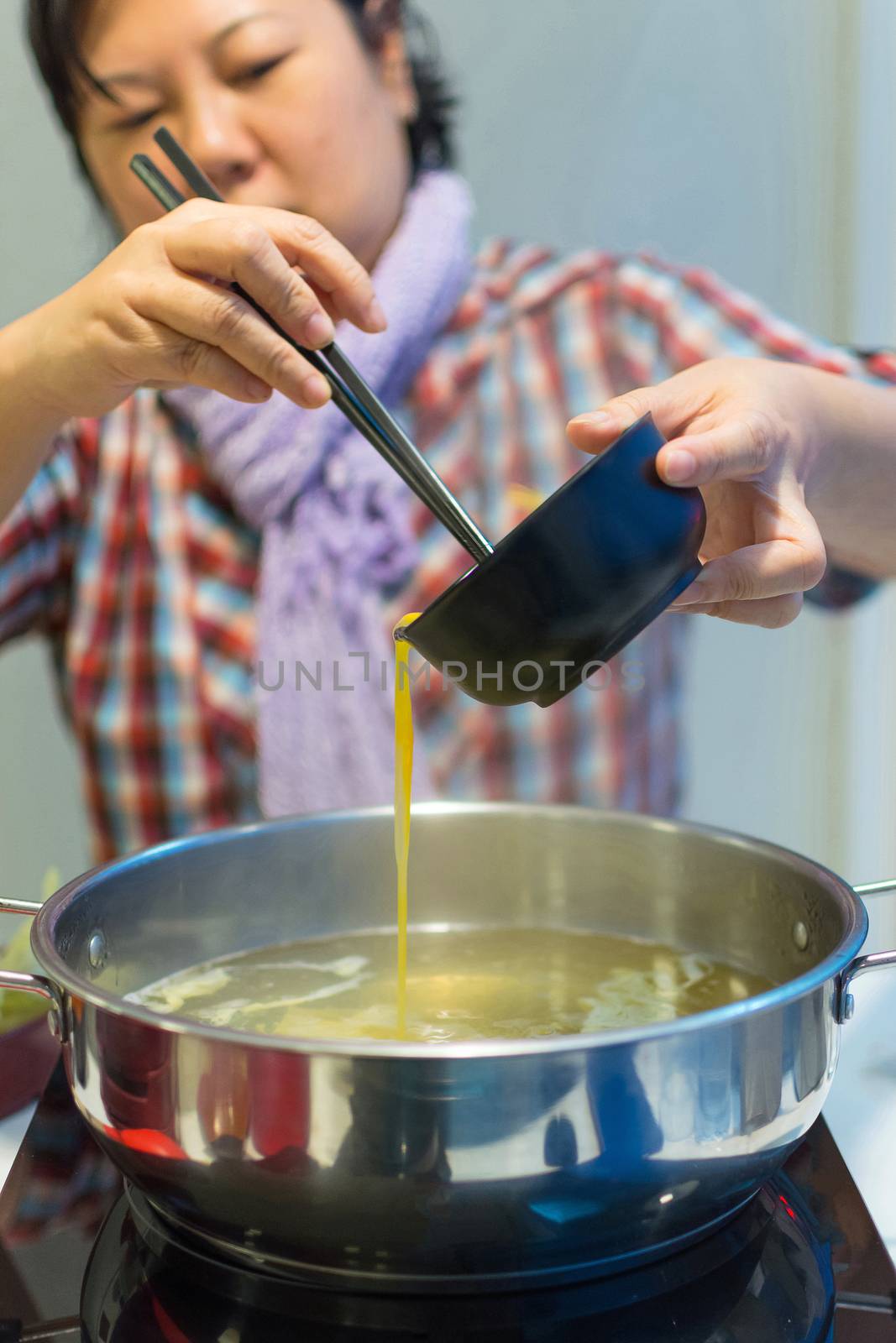 Asia woman plump body cooking food by put a flesh egg in to a hot pot for make a sukiyaki or shabu