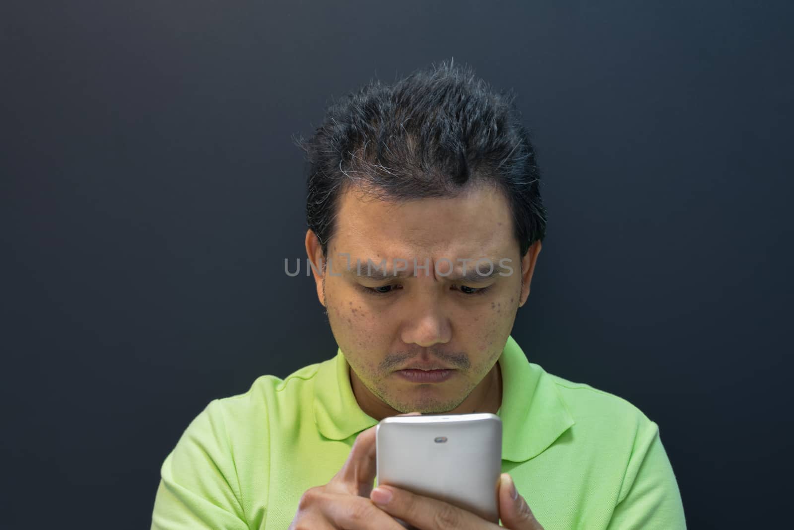 Asia man confused and worried using smartphone on black background