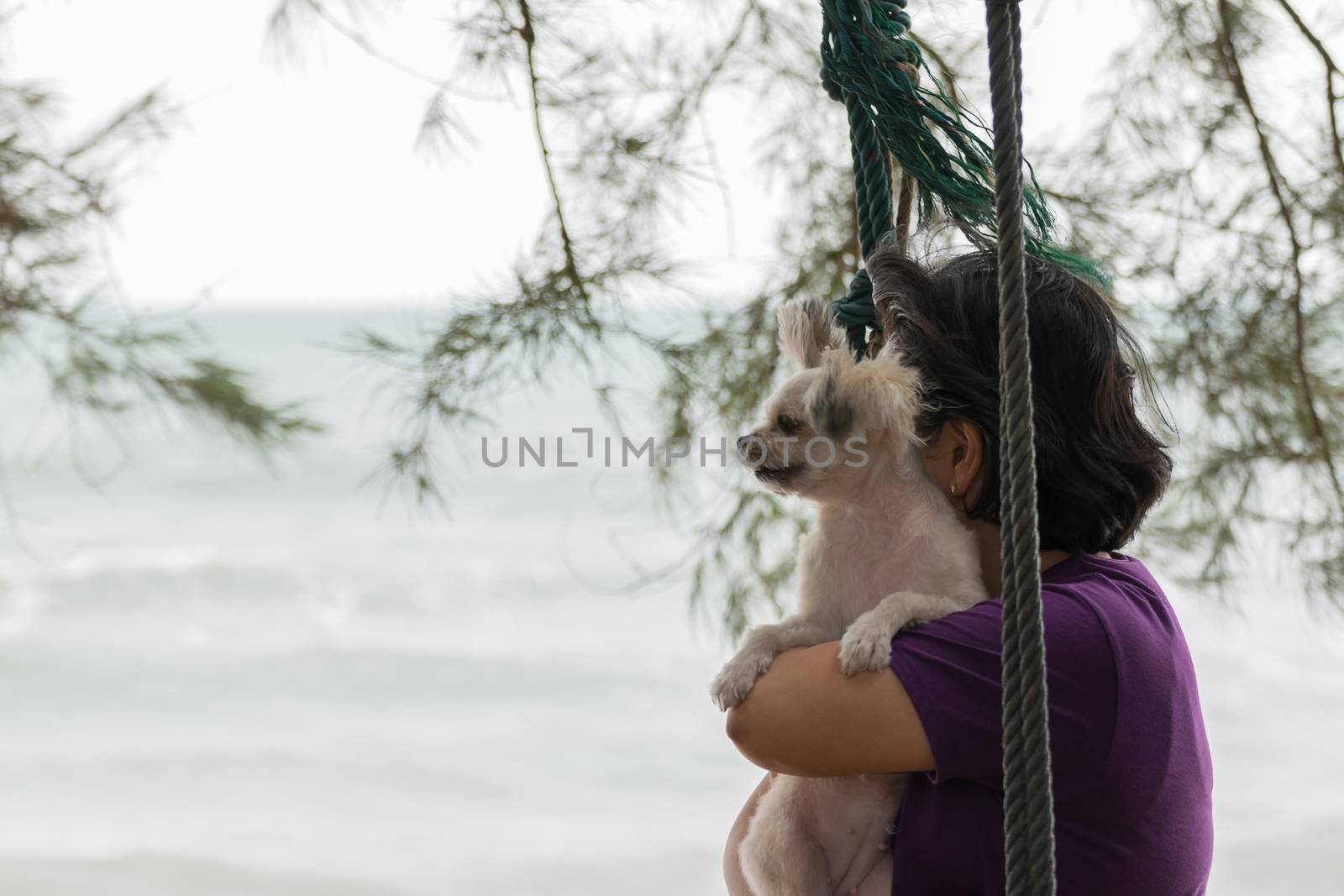 Asia woman plump body and her dog posing on swing at beach with blue sea and sky when travel