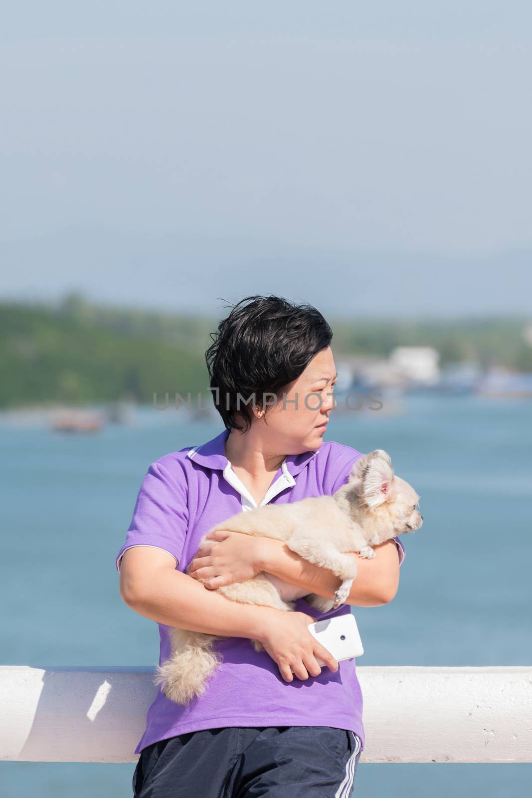 Asia woman plump body and her dog standing at estuary (river side and sea) when travel