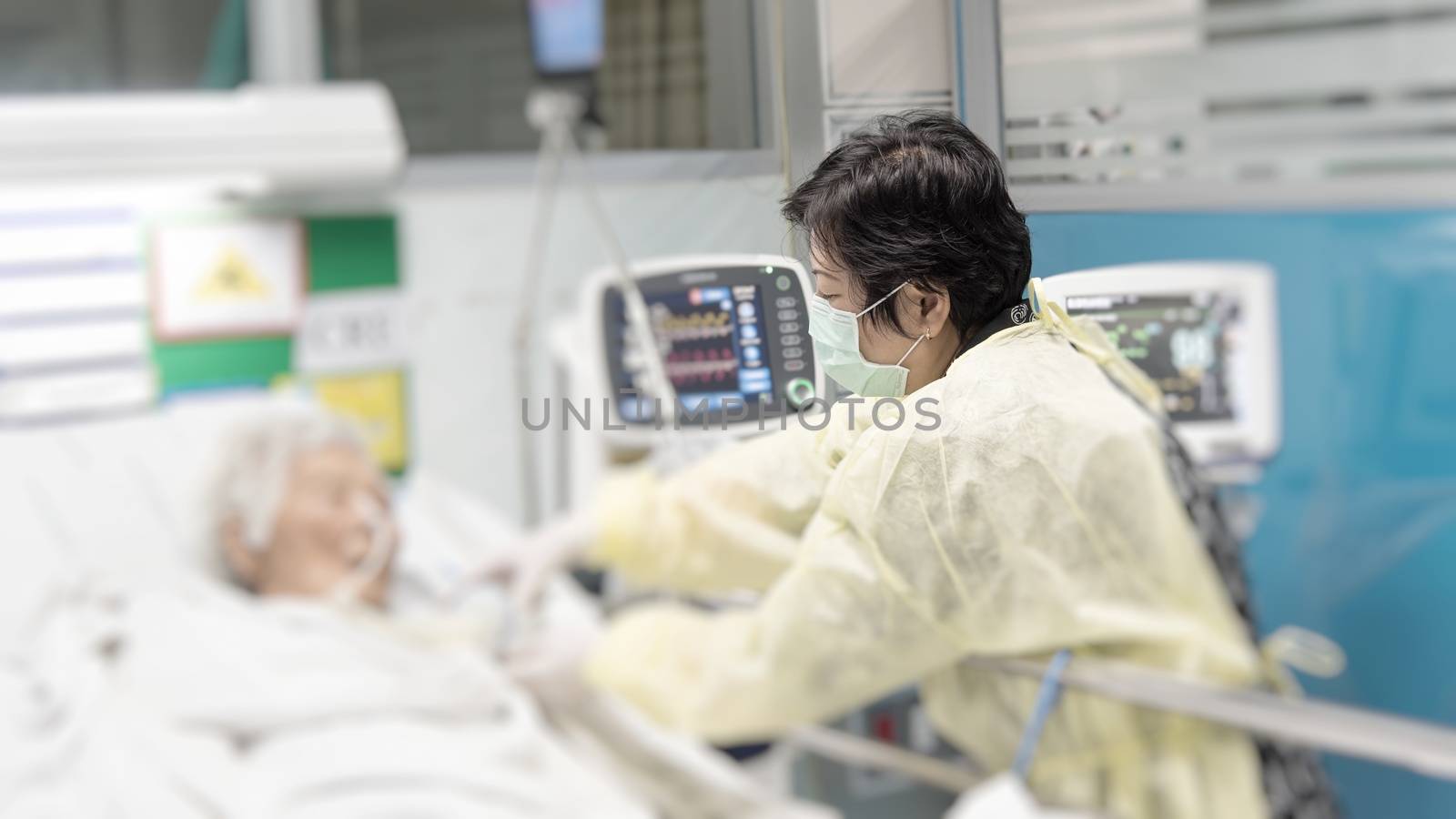 Asian women 40s years old in gown coat is a patient relative taking care of the CRE. or VRE. infected elder patient 80s years old on bed in the hospital.