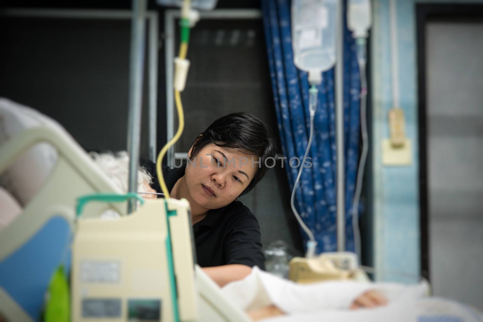 Asian women 40s years old is a patient relative taking care of the elder patient 80s years old on bed in the hospital.