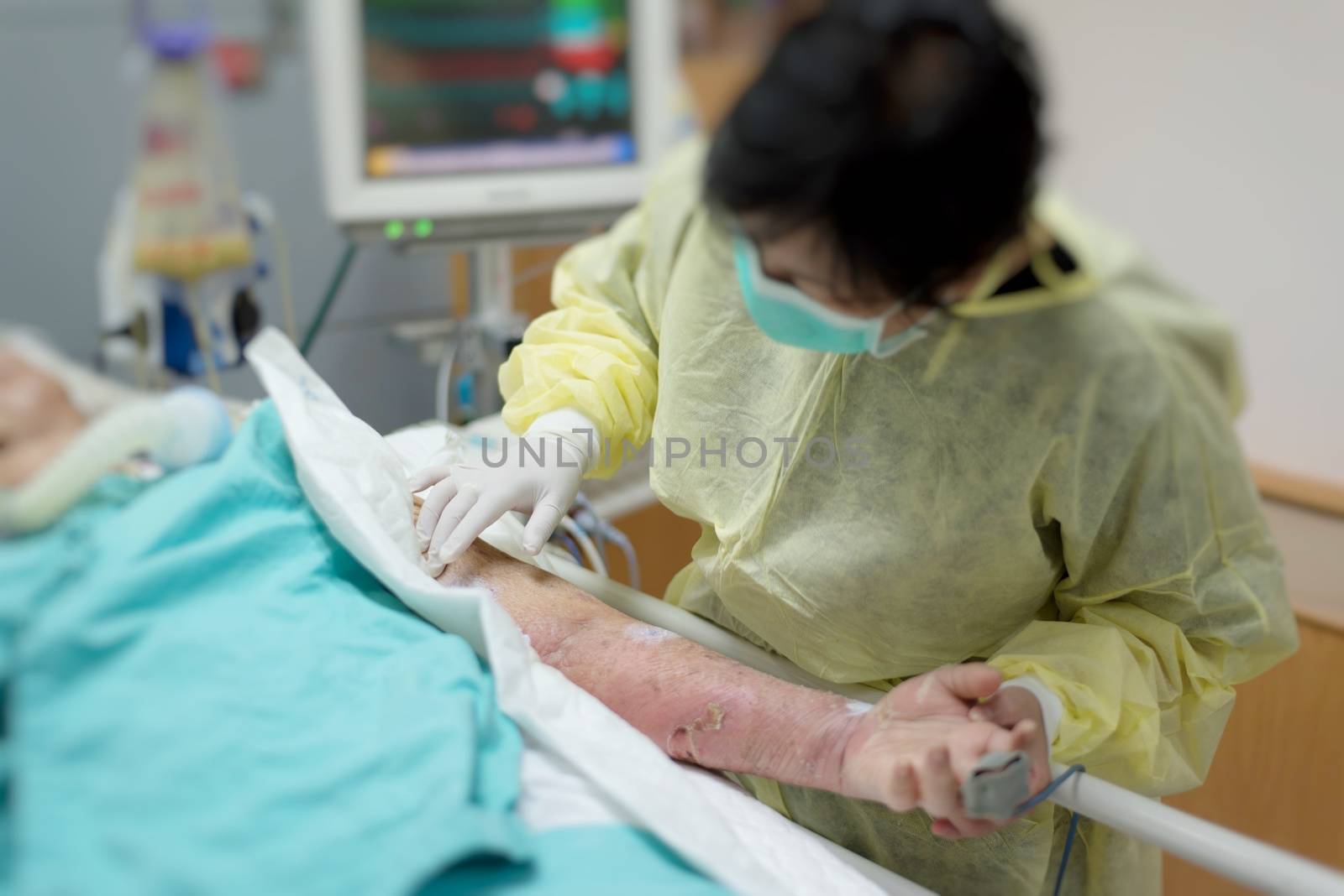 Asian women 40s years old in isolation gown non-sterile coat is a patient relative taking care of the CRE. or VRE. infected elder patient 80s years old on bed in the hospital.