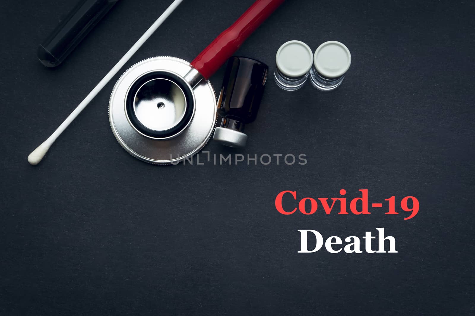 COVID-19 or CORONAVIRUS DEATH text with stethoscope, medical swab and vial on black background by silverwings