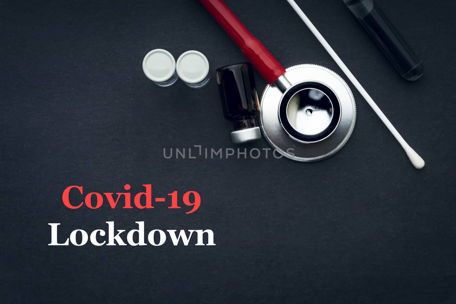 COVID-19 or CORONAVIRUS LOCKDOWN text with stethoscope, medical swab and vial on black background. Covid-19 or Coronavirus concept. 