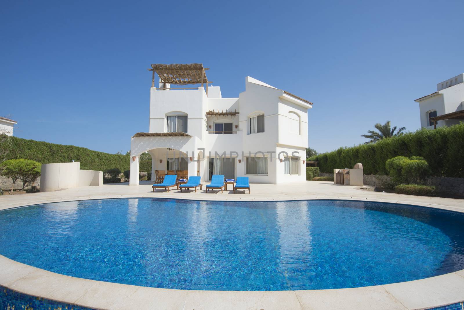Luxury villa show home in tropical summer holiday resort with swimming pool and sun loungers