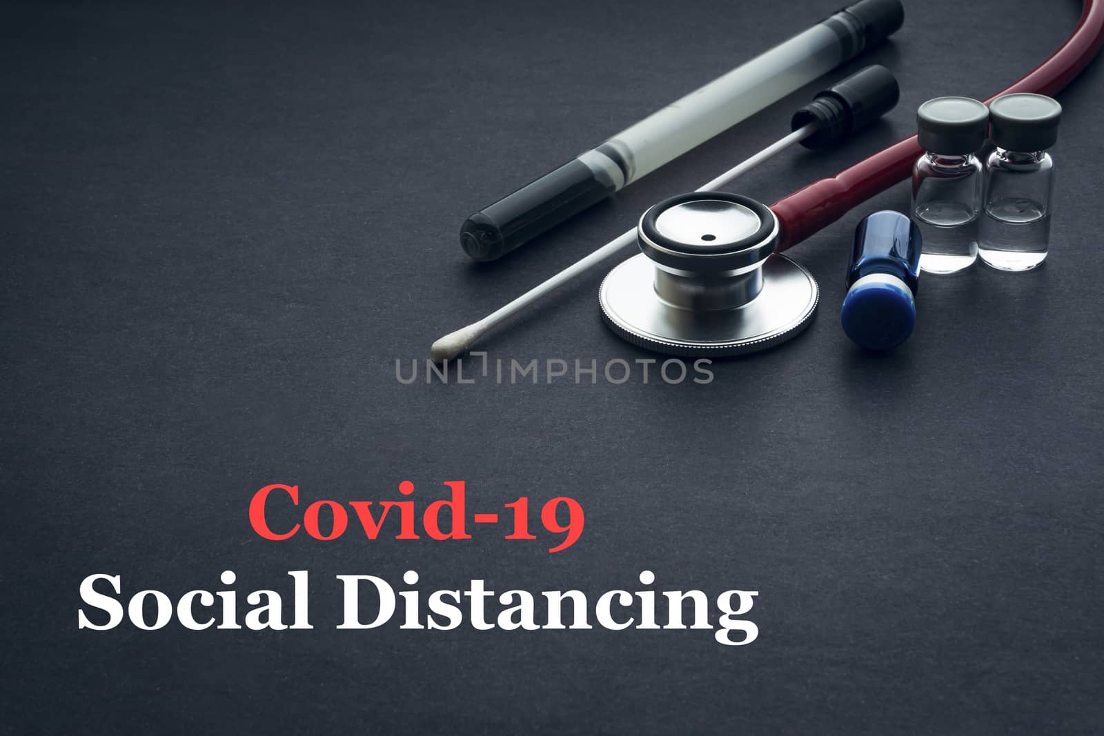 COVID-19 or CORONAVIRUS SOCIAL DISTANCING text with stethoscope, medical swab and vial on black background. Covid-19 or Coronavirus concept. 