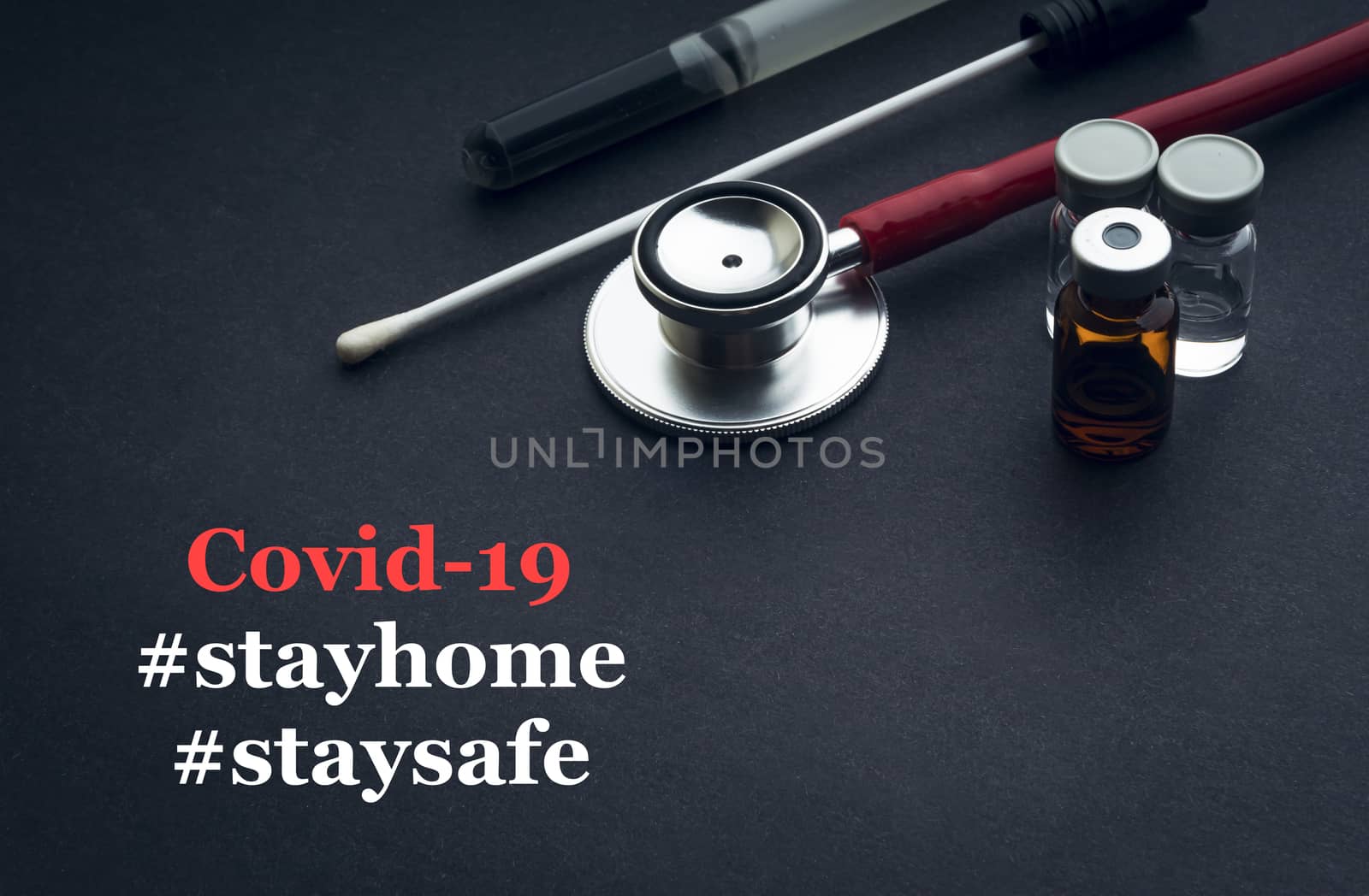 COVID-19 or CORONAVIRUS STAY HOME STAY SAFE text with stethoscope, medical swab and vial on black background. Covid-19 or Coronavirus concept. 