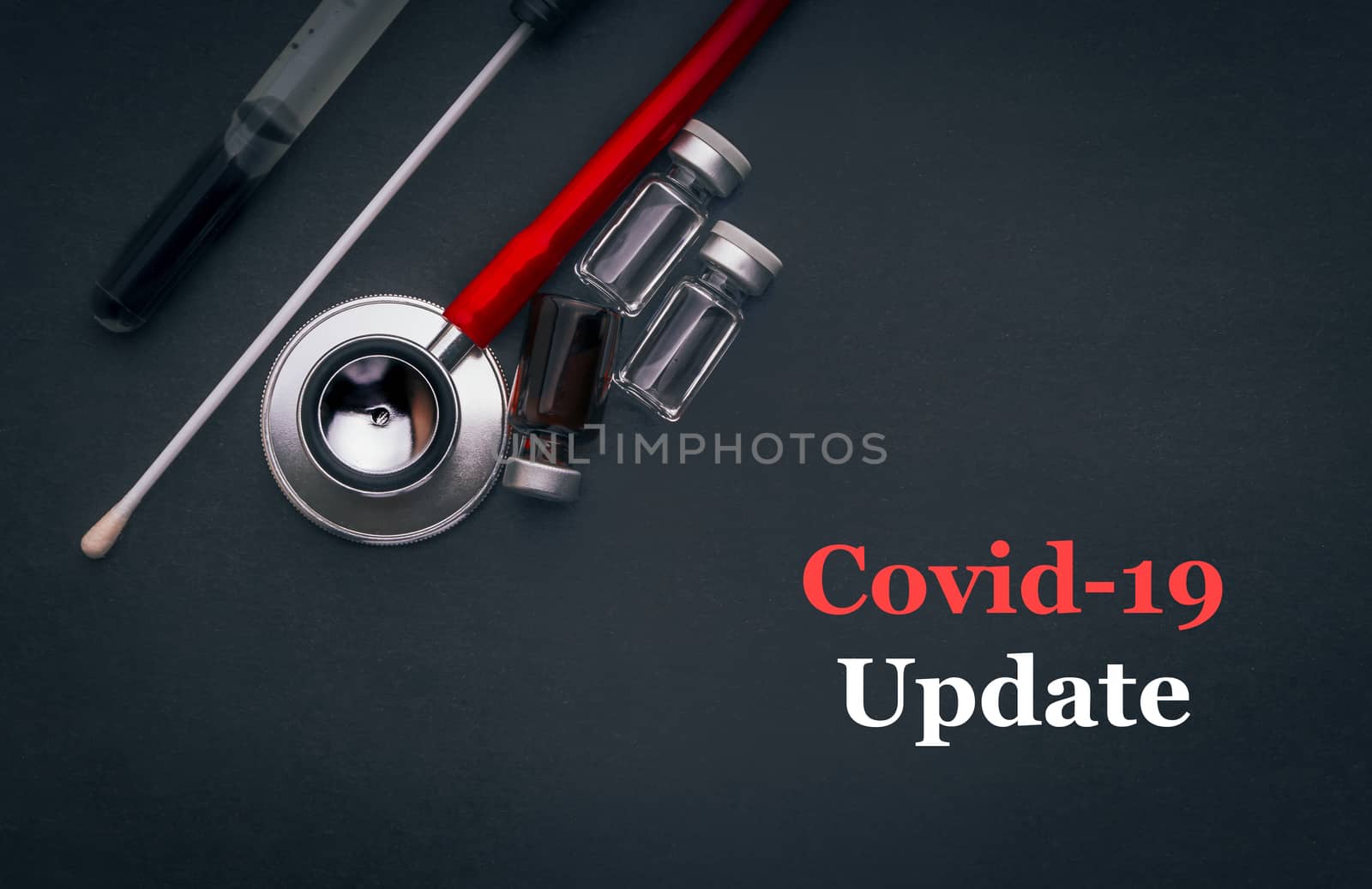 COVID-19 or CORONAVIRUS UPDATE text with stethoscope, medical swab and vial on black background by silverwings