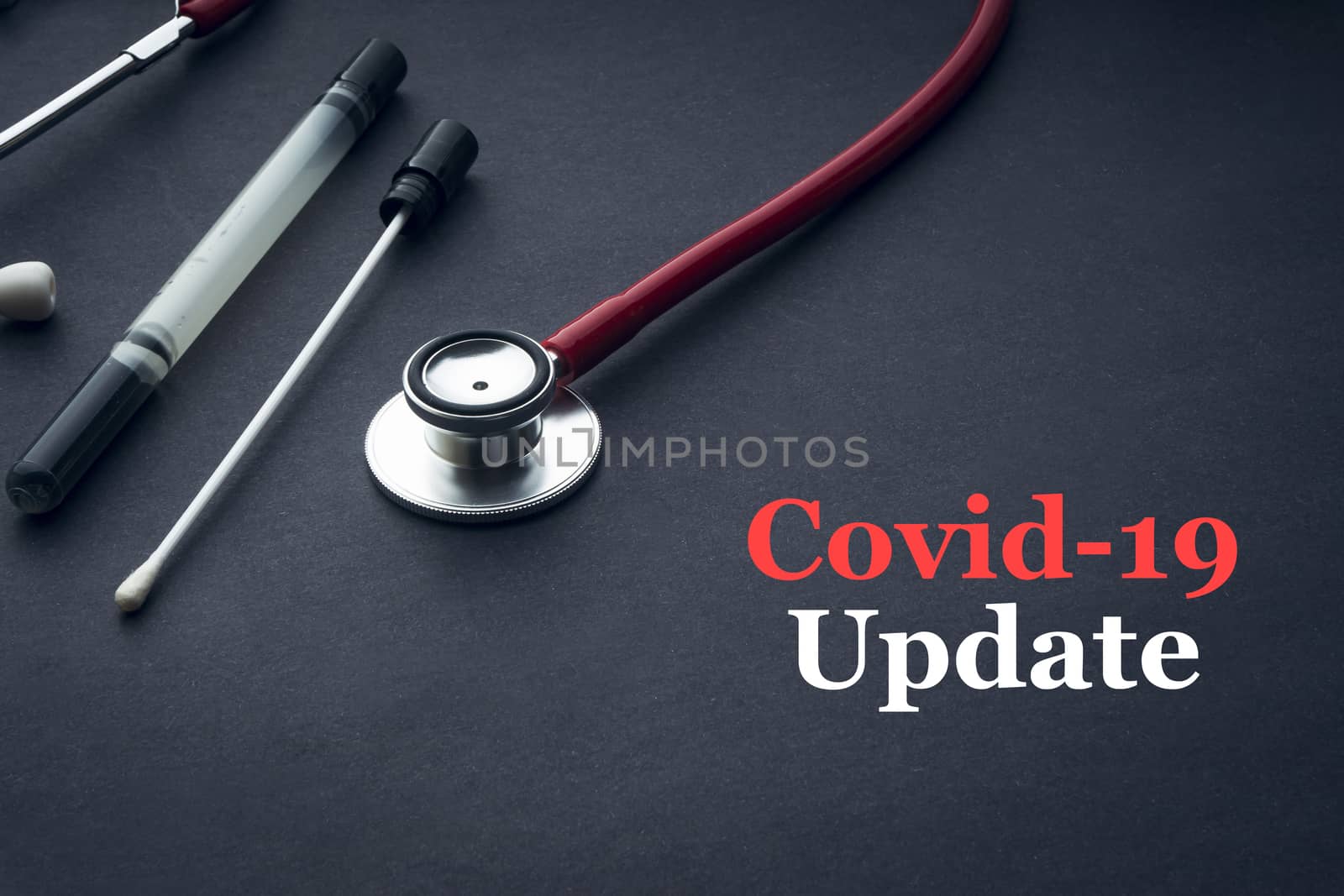 COVID-19 or CORONAVIRUS UPDATE text with stethoscope, medical swab and vial on black background. Covid-19 or Coronavirus concept. 
