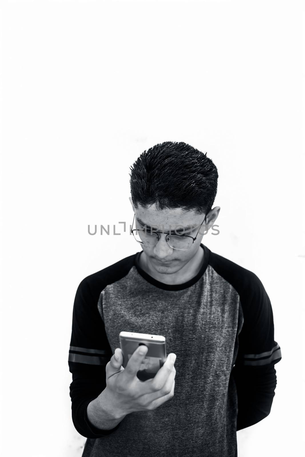 Portrait shot of young teenager wearing black colored t-shirt and using cell phone and posing or expressing various expressions on his face isolated on white. by mirzamlk