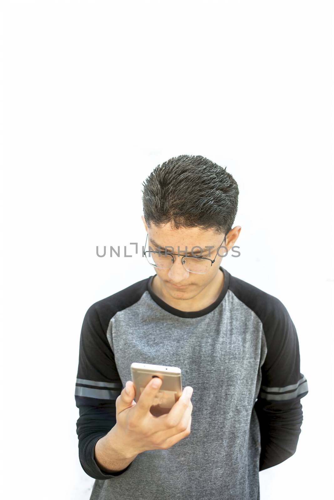 Portrait shot of young teenager wearing black colored t-shirt and using cell phone and posing or expressing various expressions on his face isolated on white.