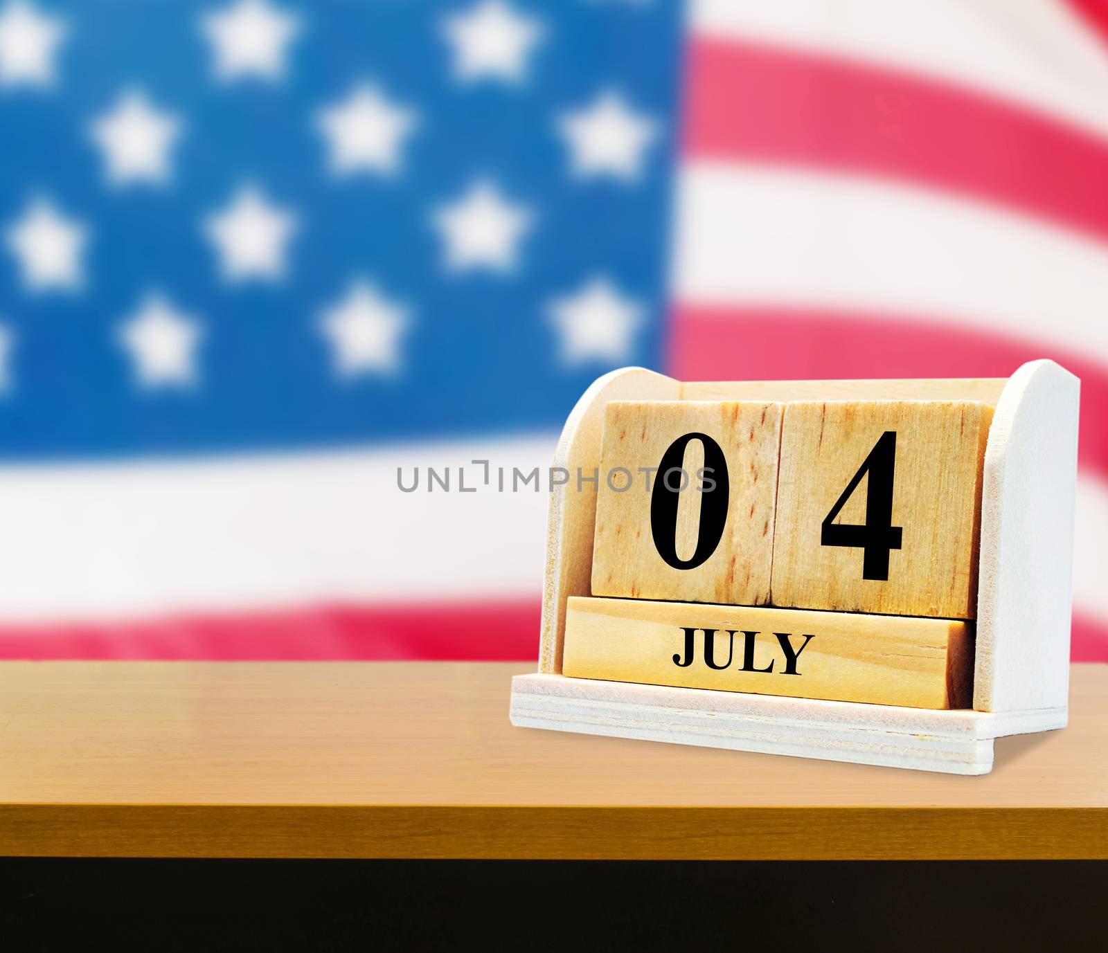 Cube shape calendar for July 04 on wooden table on usa flag background