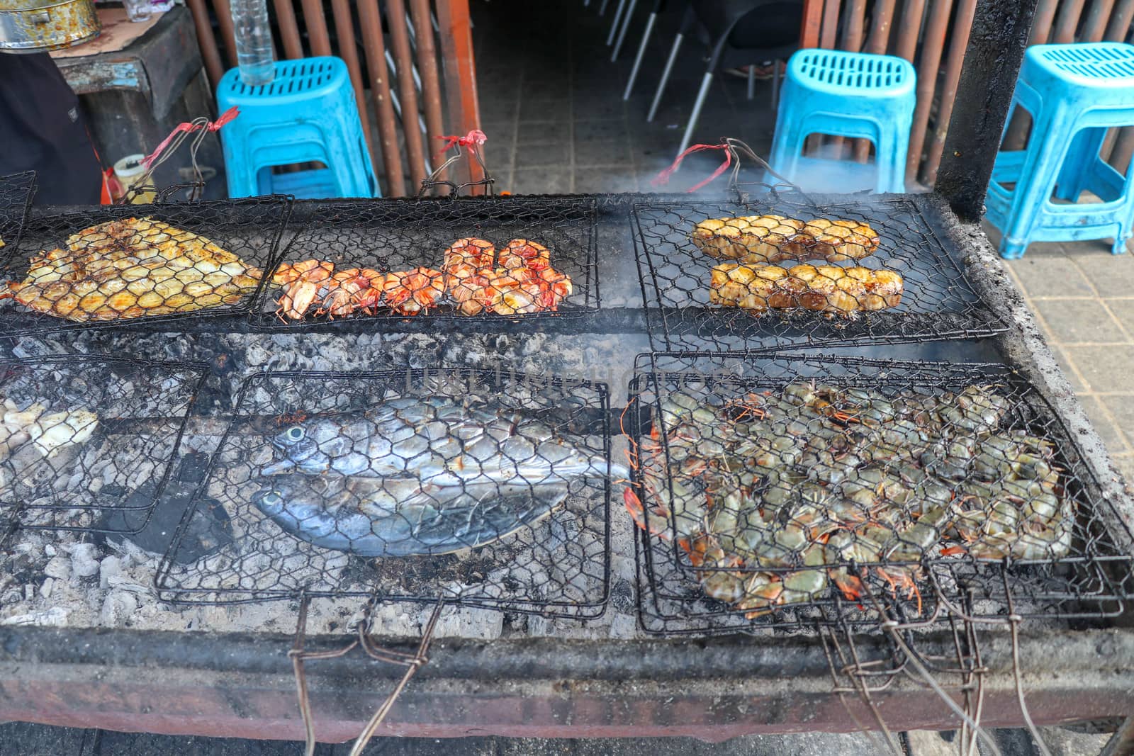 Fish barbecue. Cooking BBQ seafood on fire. Grill with burning coals. barbecue in excellent warung at the fish market on tropical Bali island in Jimbaran. Fresh, healthy and delicious seafood.