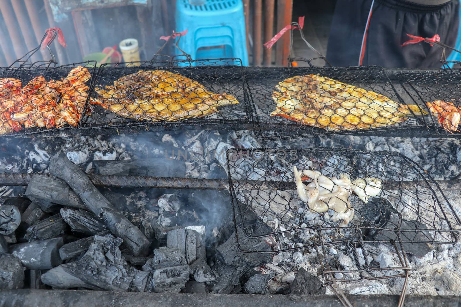 Fish barbecue. Cooking BBQ seafood on fire. Grill with burning coals. barbecue in excellent warung at the fish market on tropical Bali island in Jimbaran. Fresh, healthy and delicious seafood.