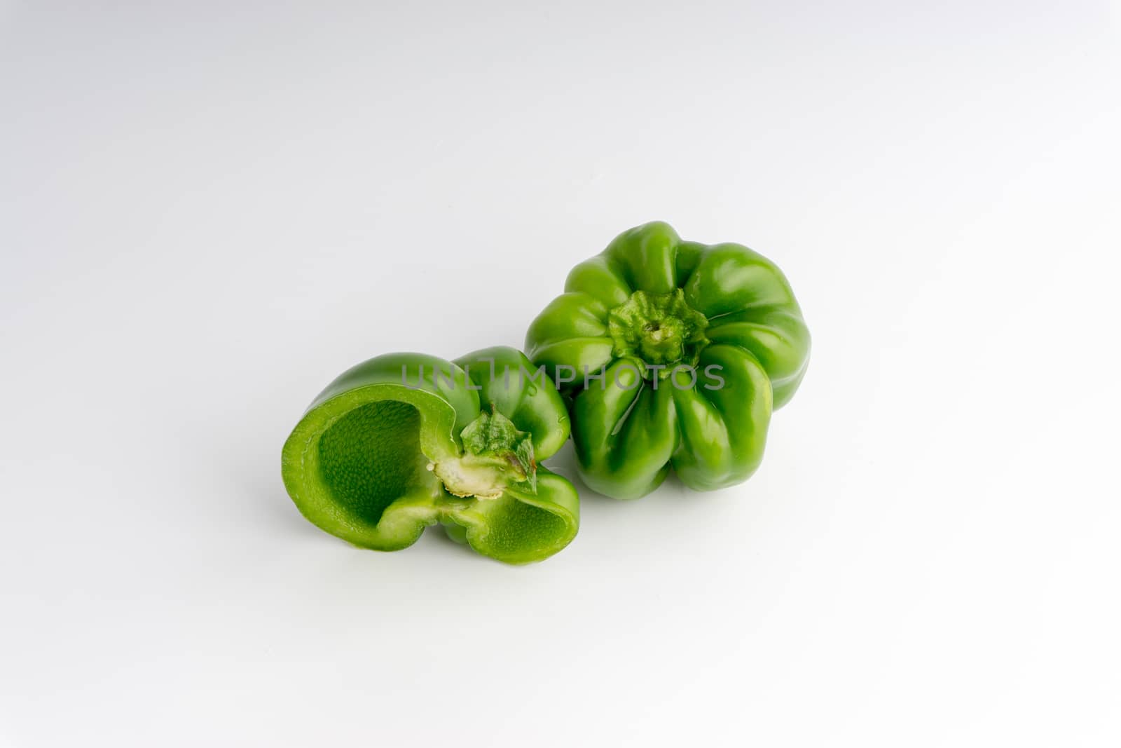 Fresh green bell peppers (capsicum) on a white background. Selective focus and crop fragment