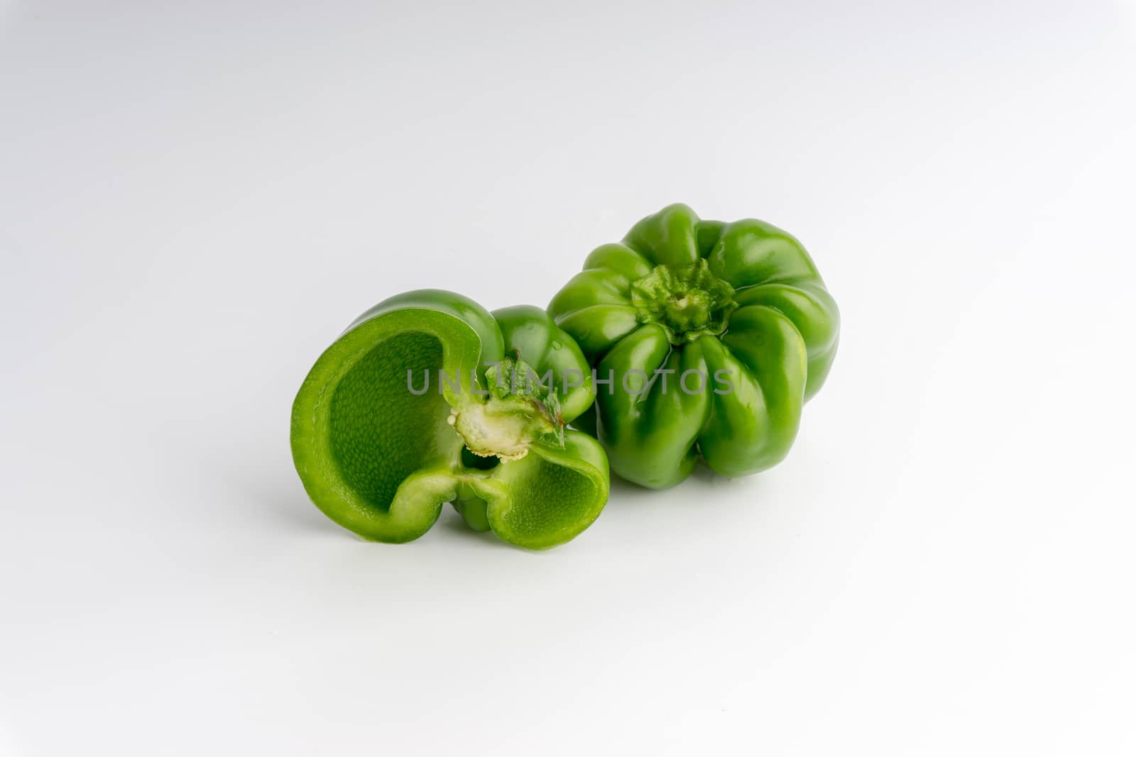 Fresh green bell peppers (capsicum) on a white background. Selective focus and crop fragment