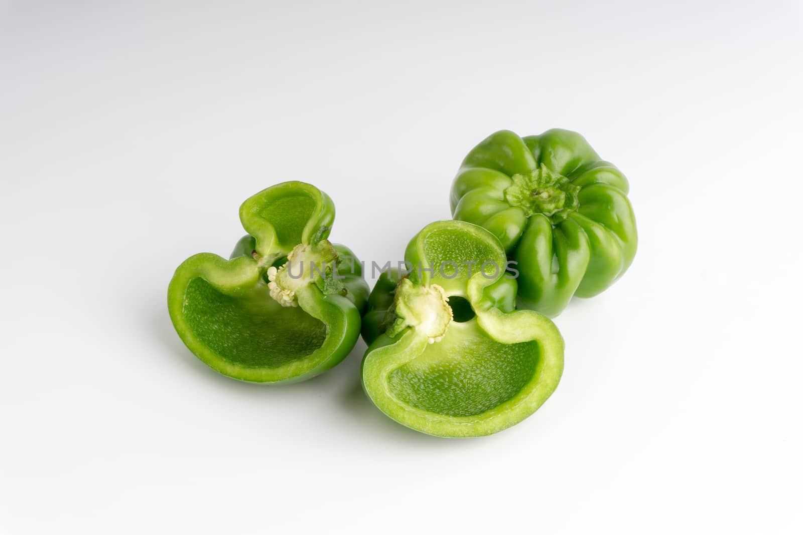 Fresh green bell peppers (capsicum) on a white background. Selective focus and crop fragment