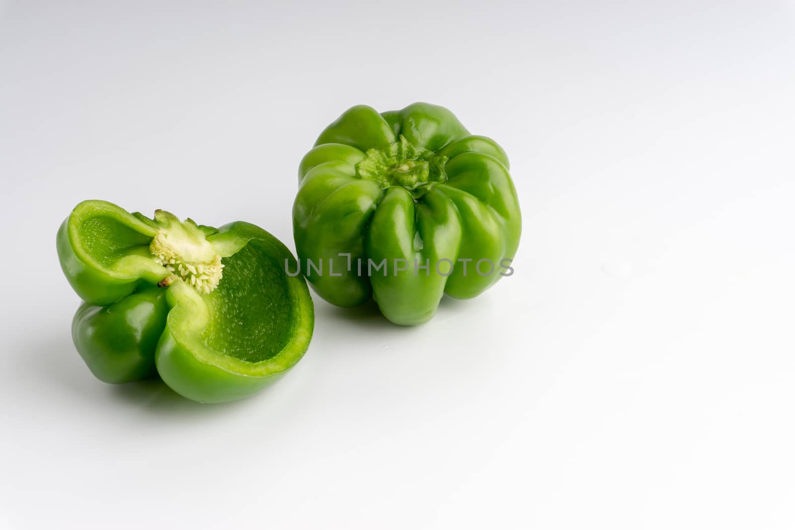 Fresh green bell peppers (capsicum) on a white background. Selective focus and crop fragment