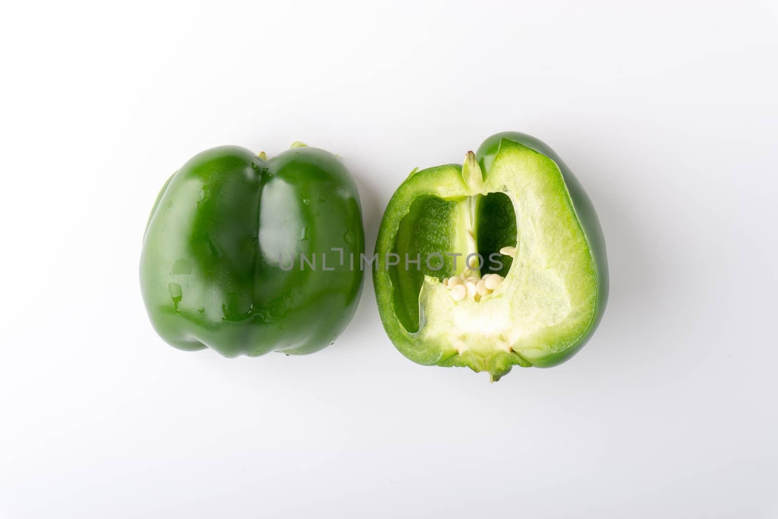 Fresh green bell peppers (capsicum) on a white background. Selective focus and crop fragment