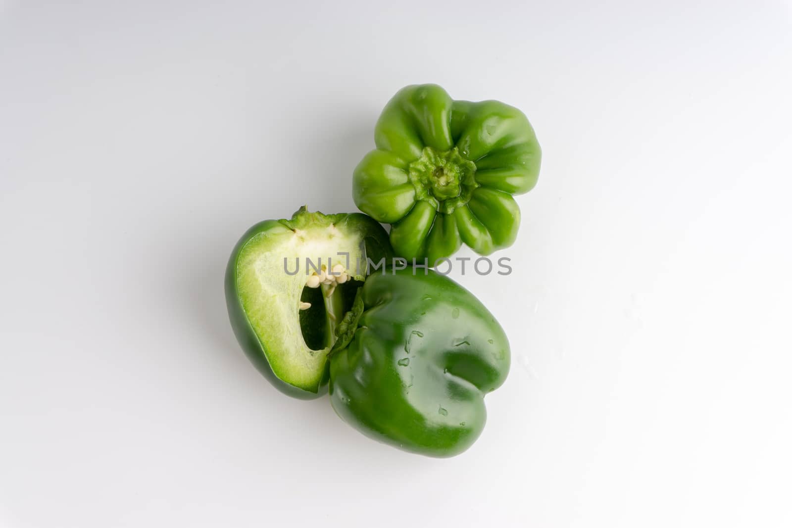 Fresh green bell peppers (capsicum) on a white background. Selective focus and crop fragment