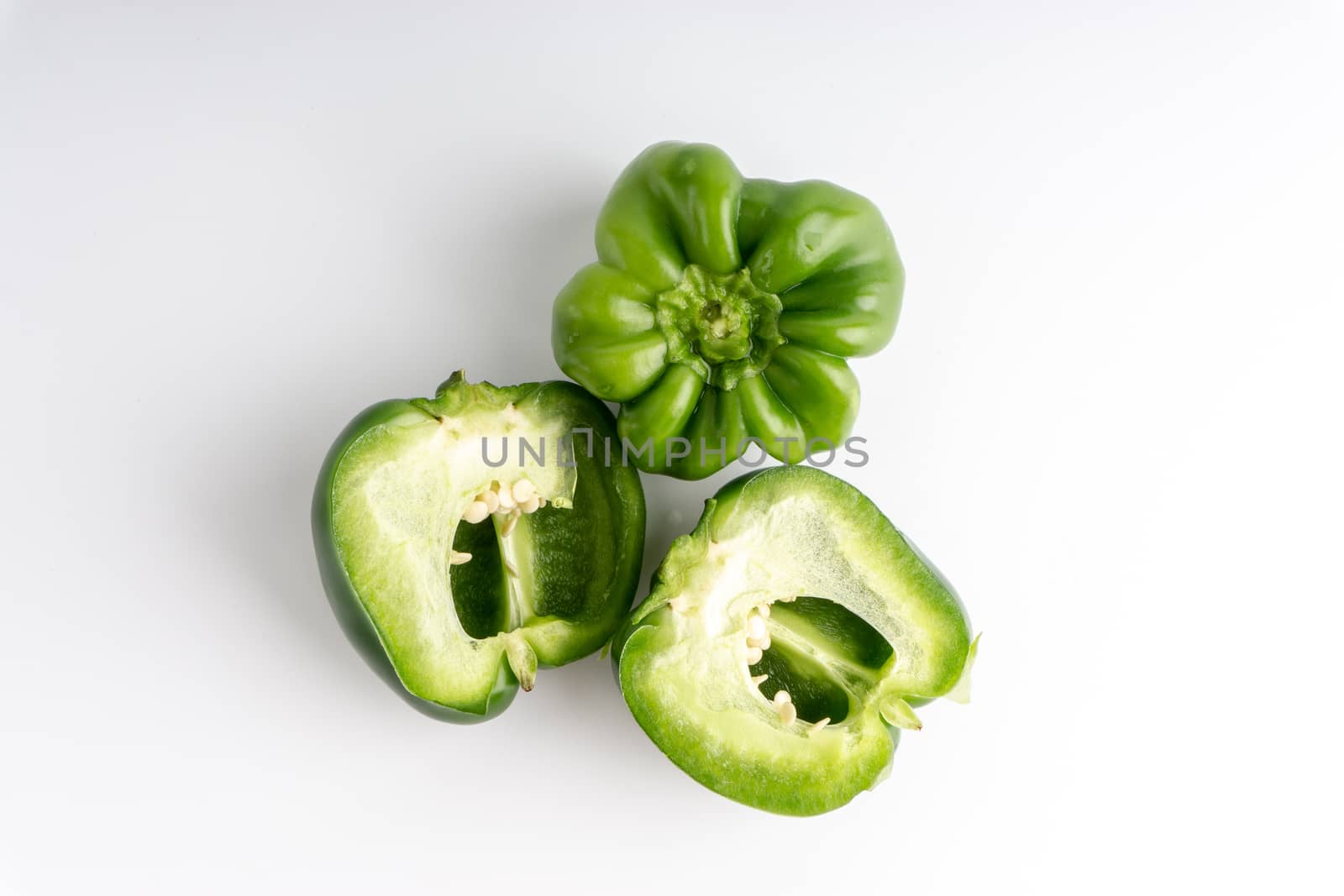 Fresh green bell peppers (capsicum) on a white background. Selective focus and crop fragment