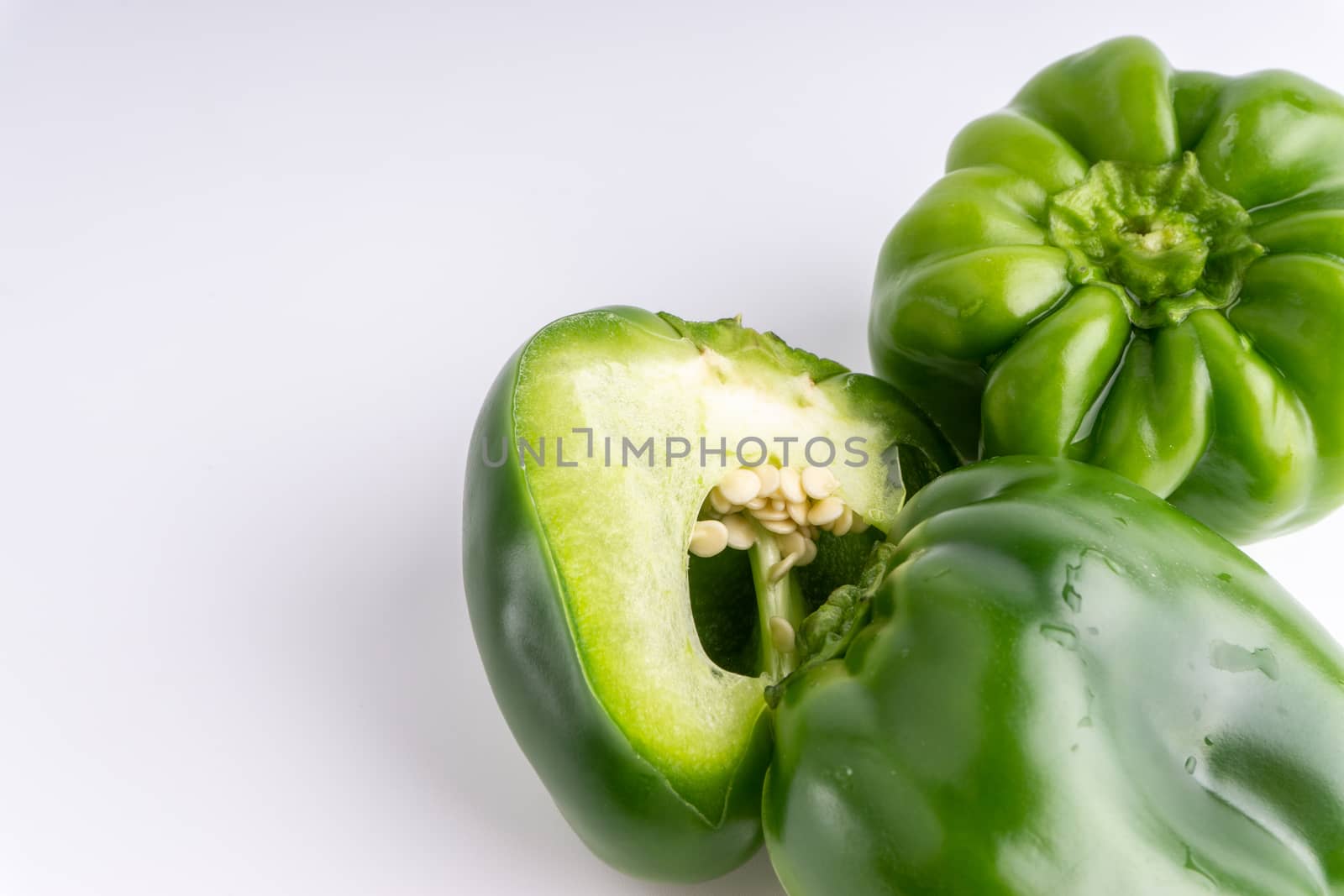 Fresh green bell peppers (capsicum) on a white background. Selective focus and crop fragment