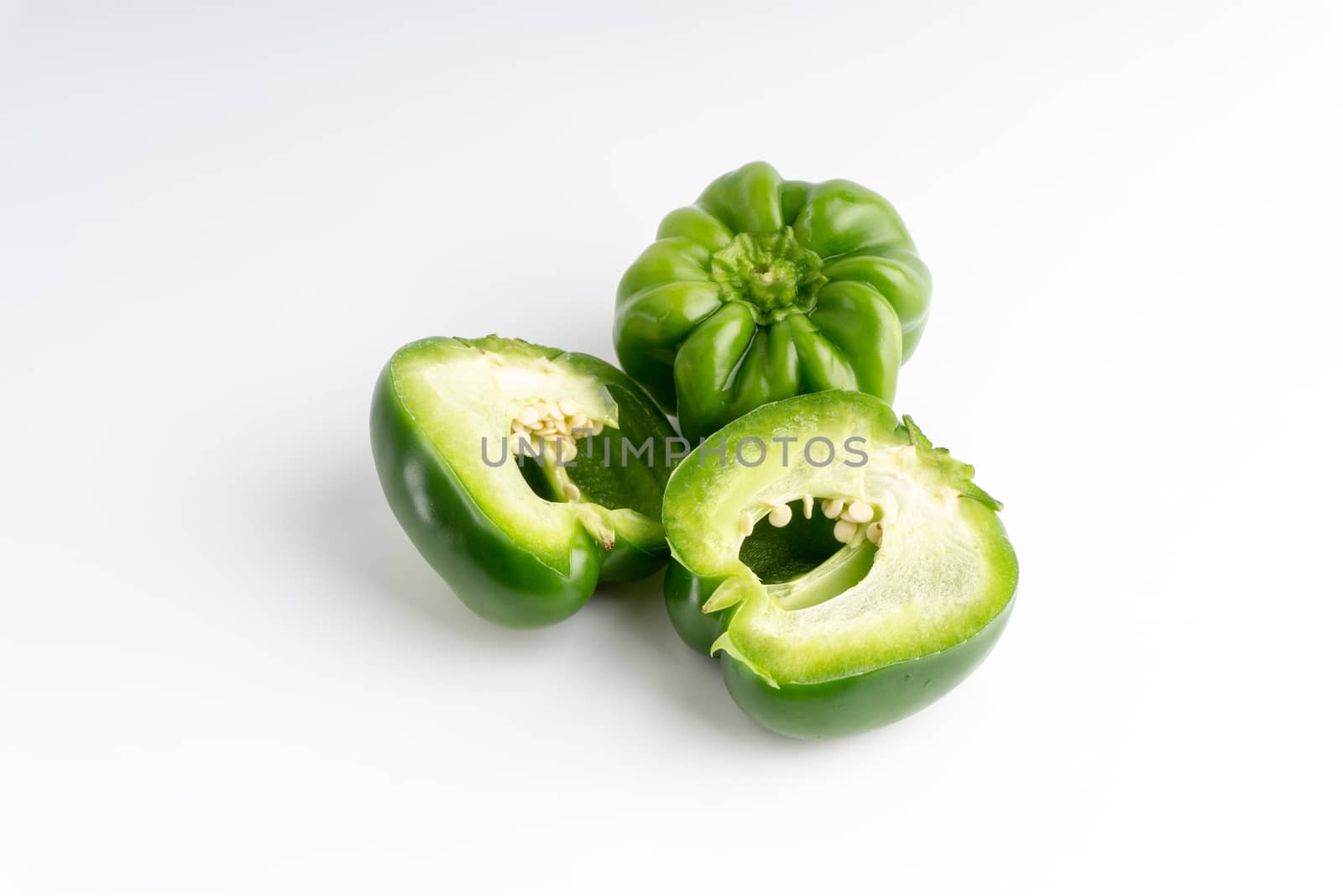 Fresh green bell peppers (capsicum) on a white background. Selective focus and crop fragment