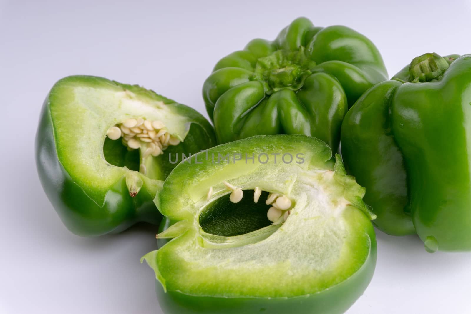 Fresh green bell peppers (capsicum) on a white background. Selective focus and crop fragment