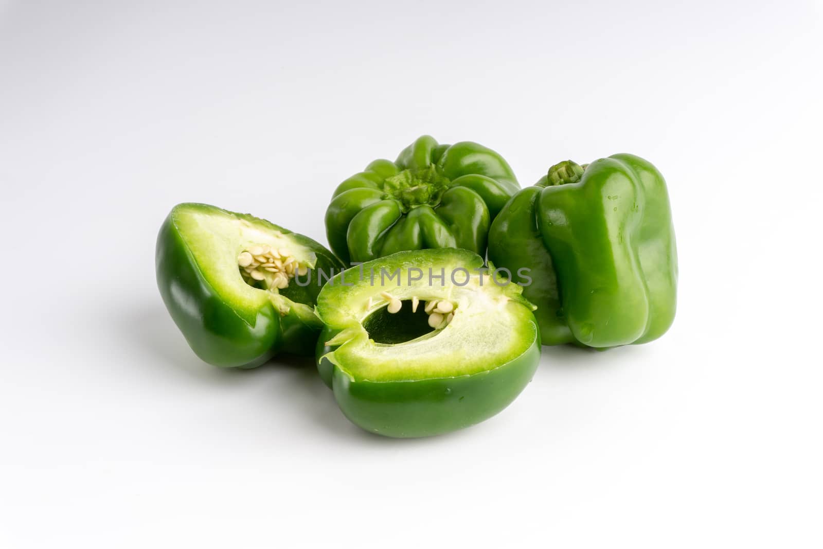 Fresh green bell peppers (capsicum) on a white background. Selective focus and crop fragment