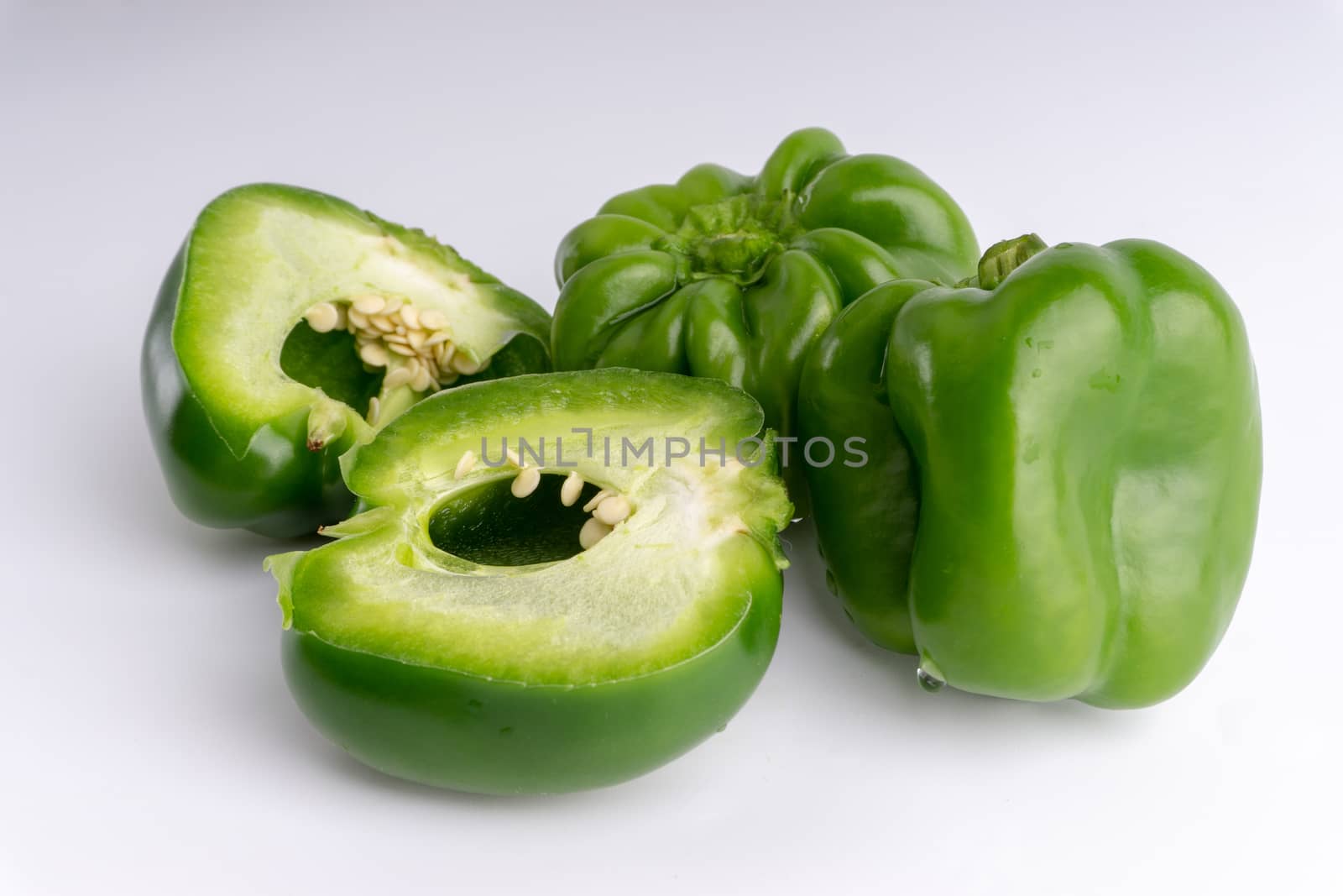 Fresh green bell peppers (capsicum) on a white background. Selective focus and crop fragment