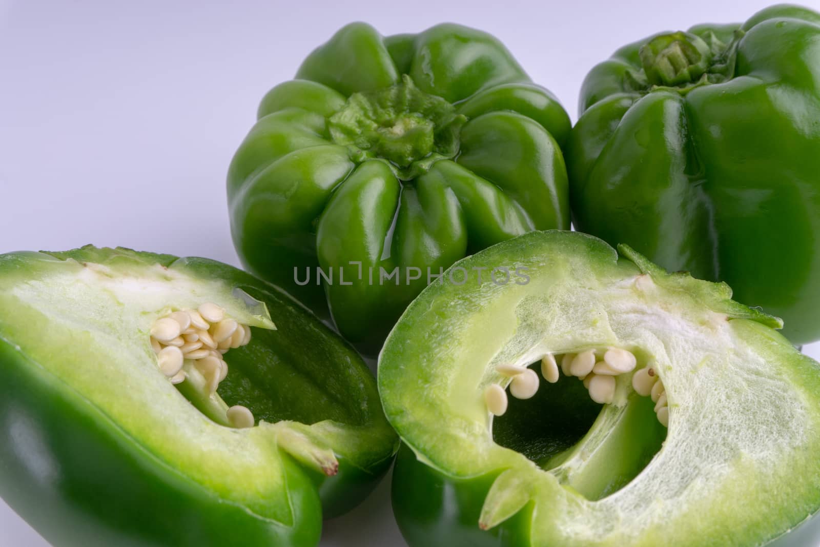 Fresh green bell peppers (capsicum) on a white background. Selective focus and crop fragment