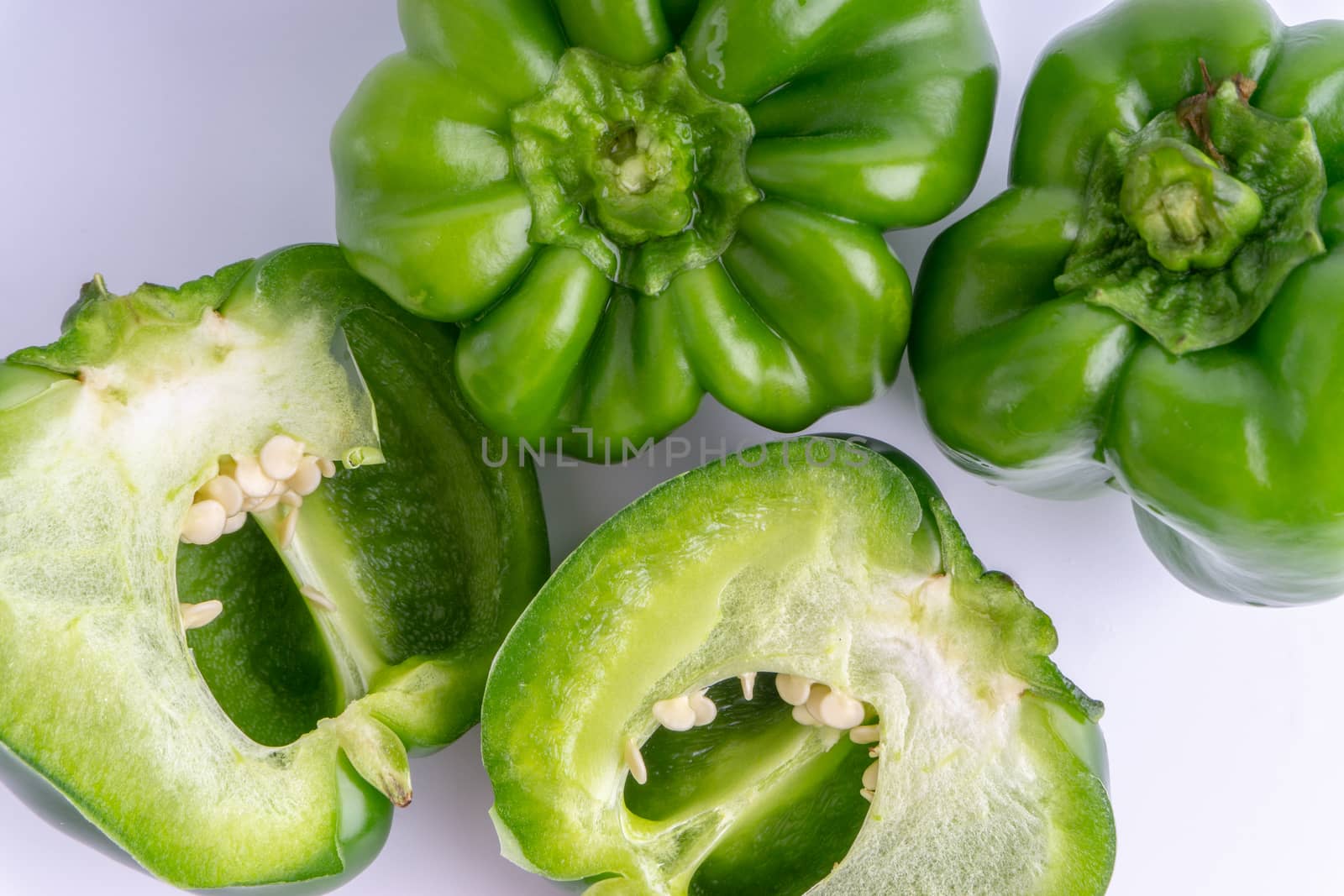 Fresh green bell peppers (capsicum) on a white background. Selective focus and crop fragment