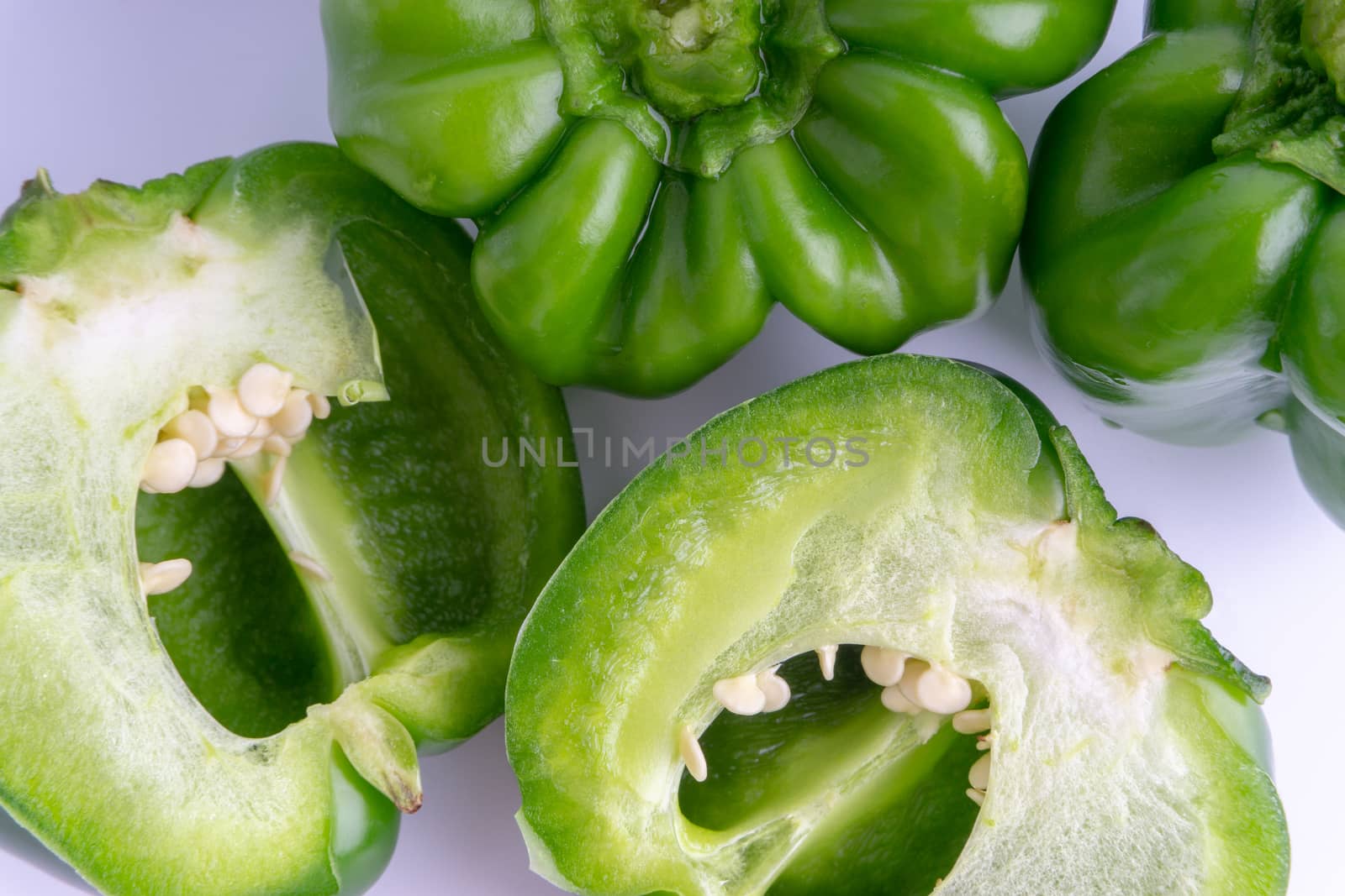 Fresh green bell peppers (capsicum) on a white background. Selective focus and crop fragment