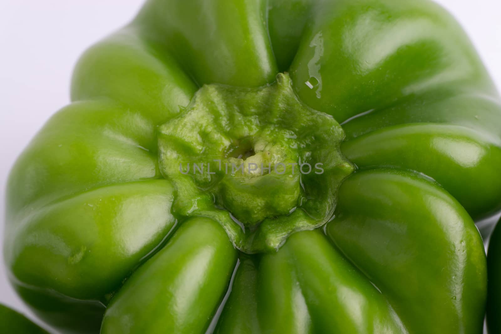 Fresh green bell peppers (capsicum) on a white background. Selective focus and crop fragment