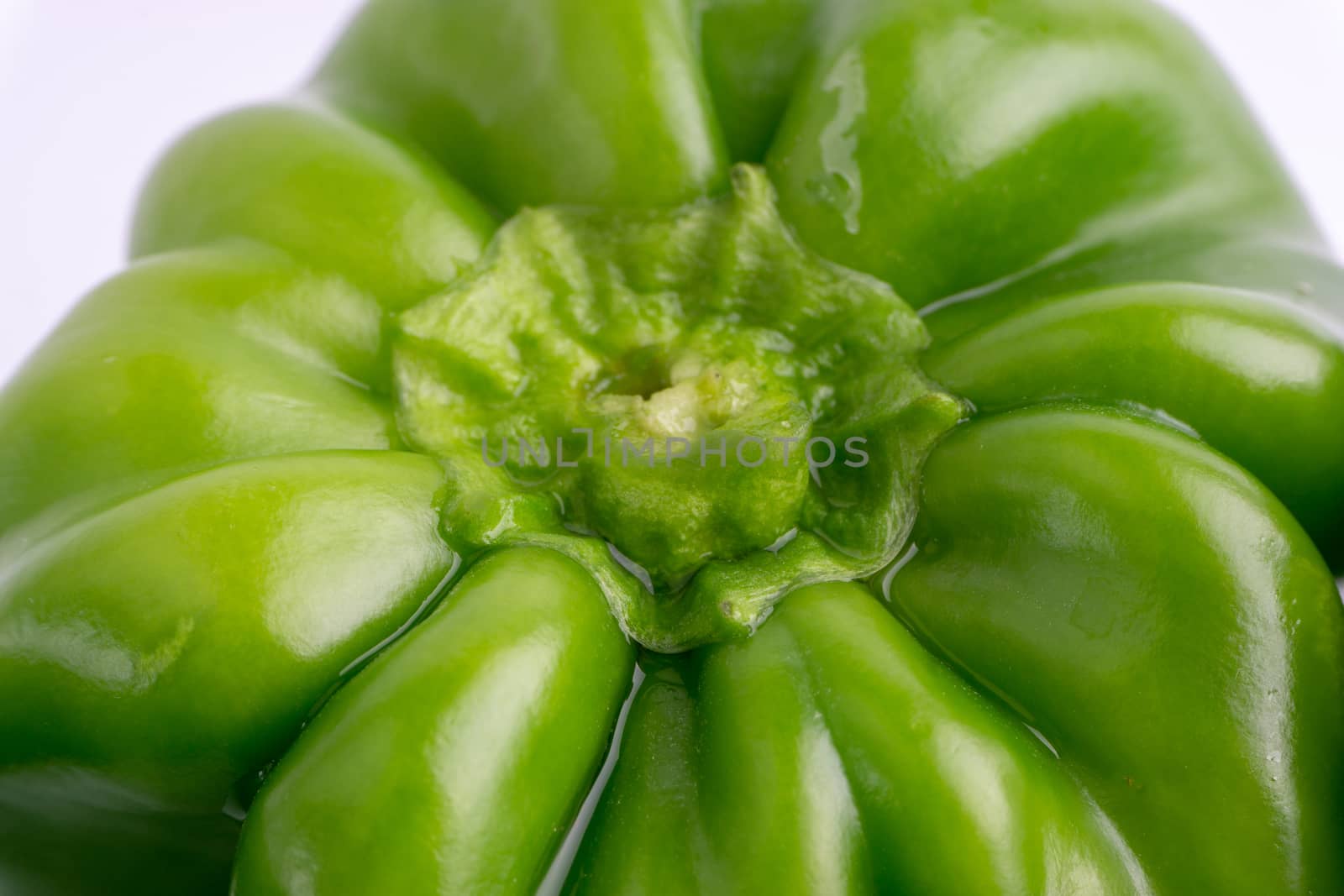 Fresh green bell peppers (capsicum) on a white background. Selective focus and crop fragment