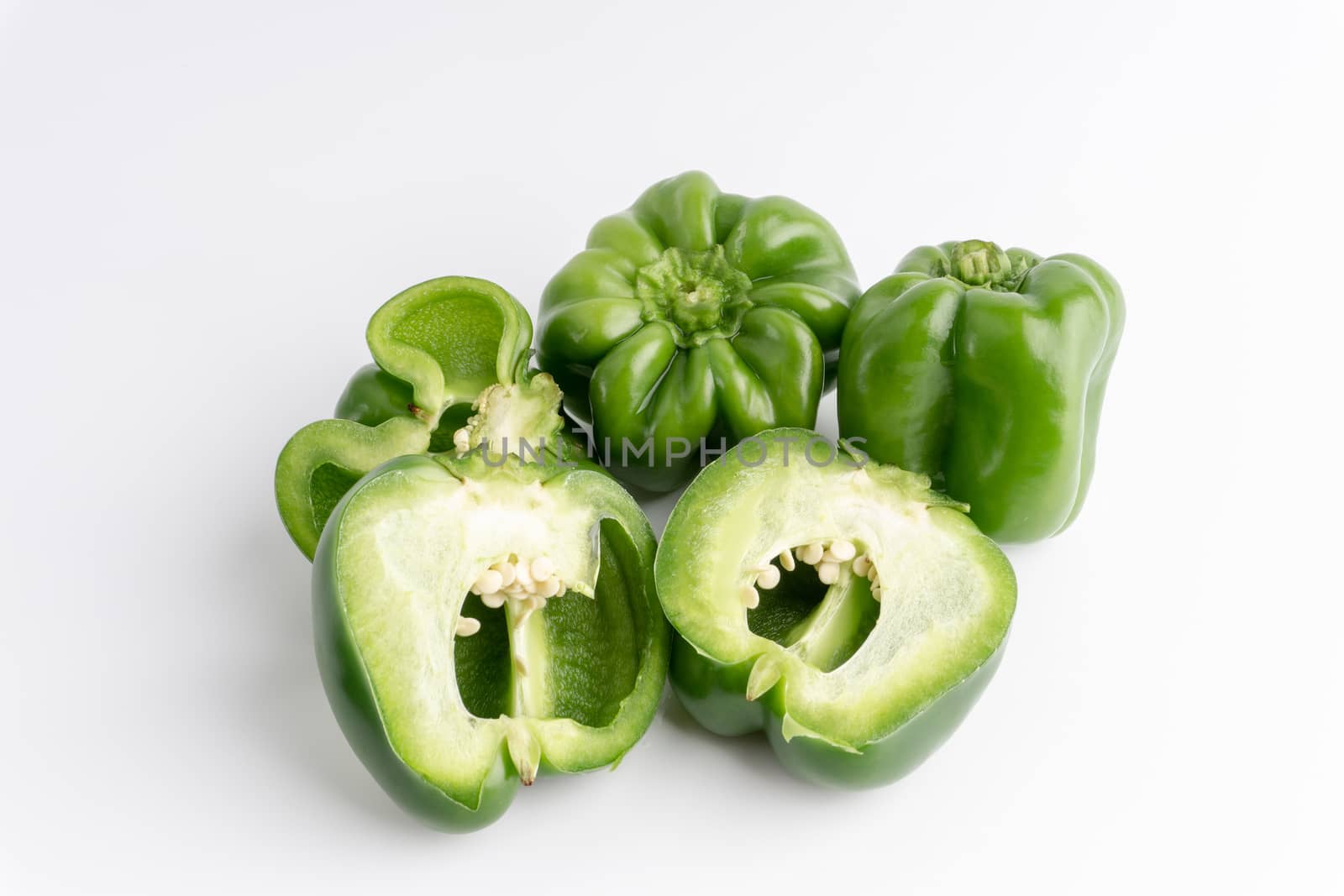 Fresh green bell peppers (capsicum) on a white background. Selective focus and crop fragment