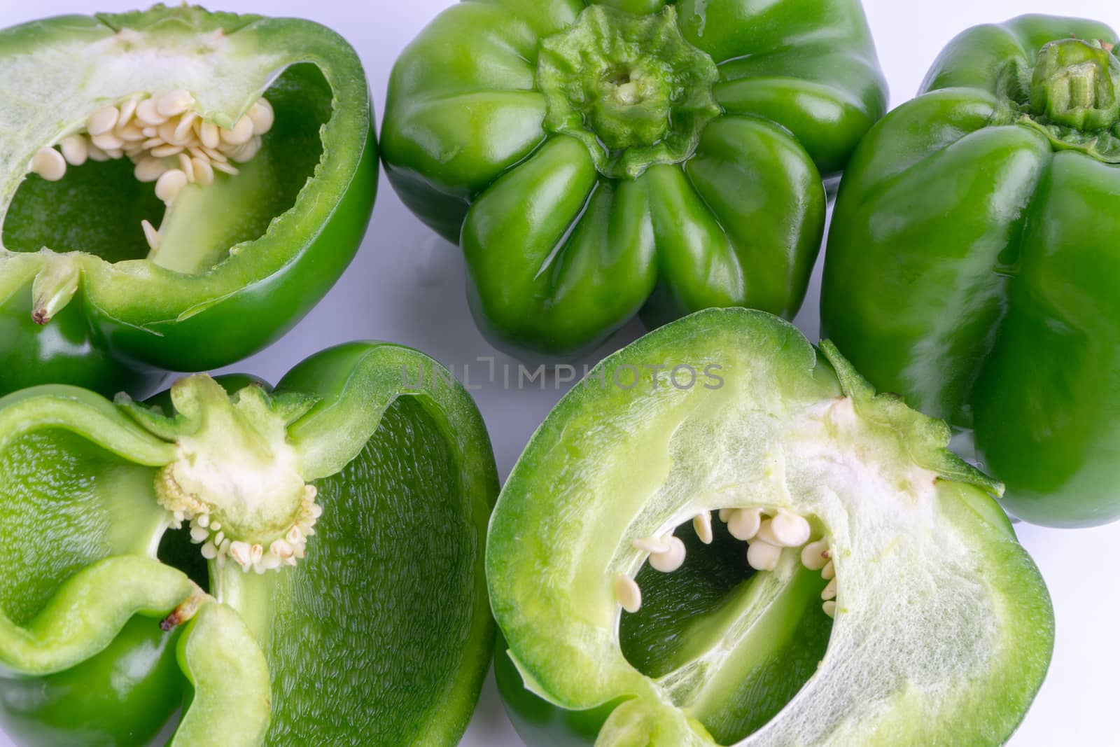 Fresh green bell peppers (capsicum) on a white background. Selective focus and crop fragment