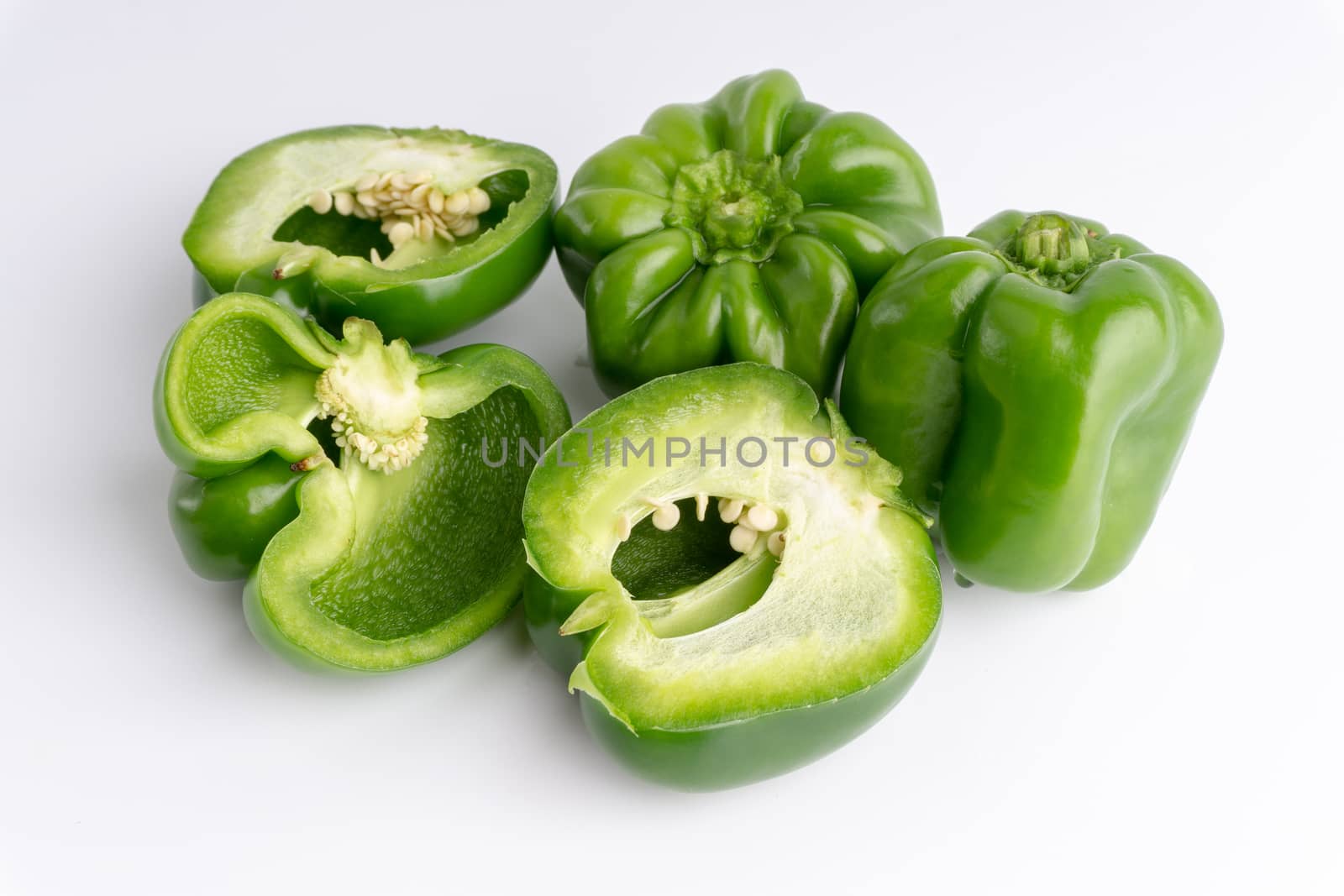 Fresh green bell peppers (capsicum) on a white background. Selective focus and crop fragment