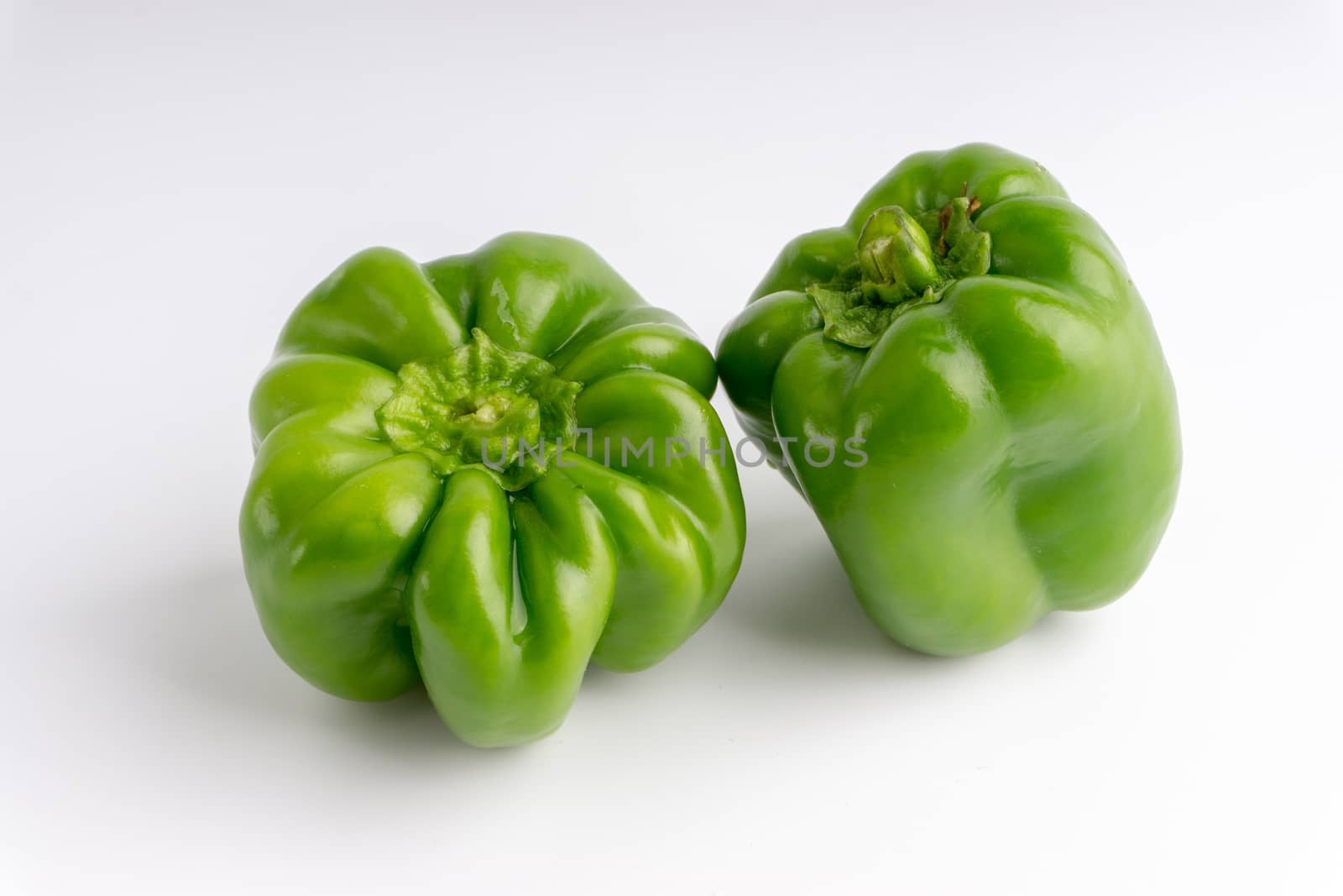 Fresh green bell peppers (capsicum) on a white background. Selective focus and crop fragment