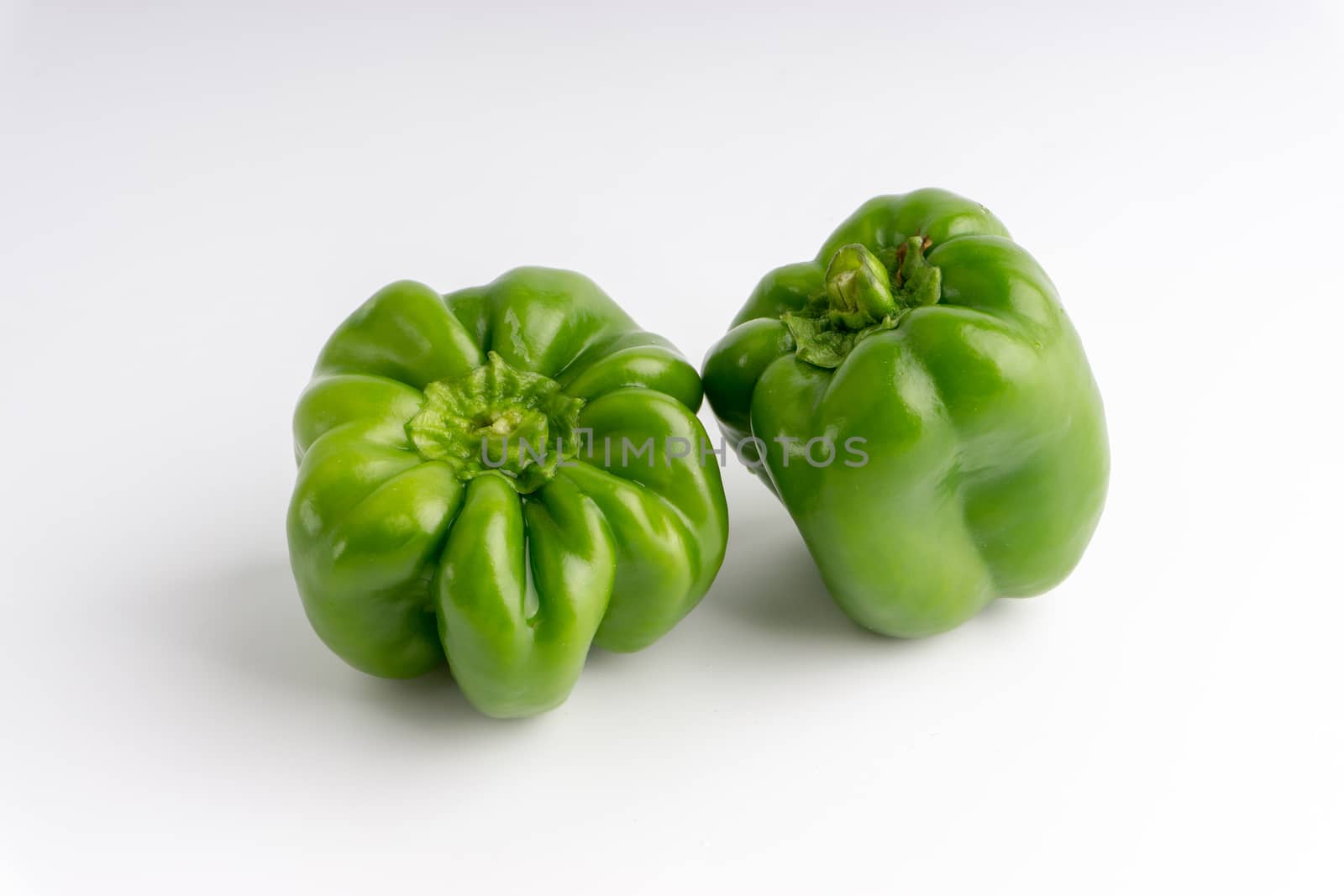 Fresh green bell peppers (capsicum) on a white background. Selective focus and crop fragment