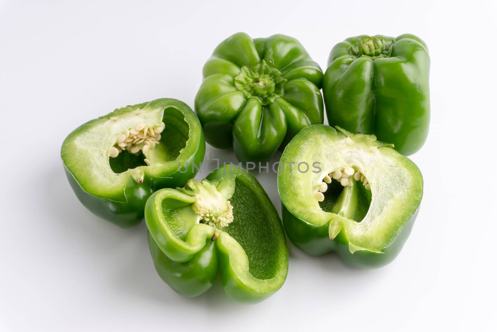 Fresh green bell peppers (capsicum) on a white background. Selective focus and crop fragment