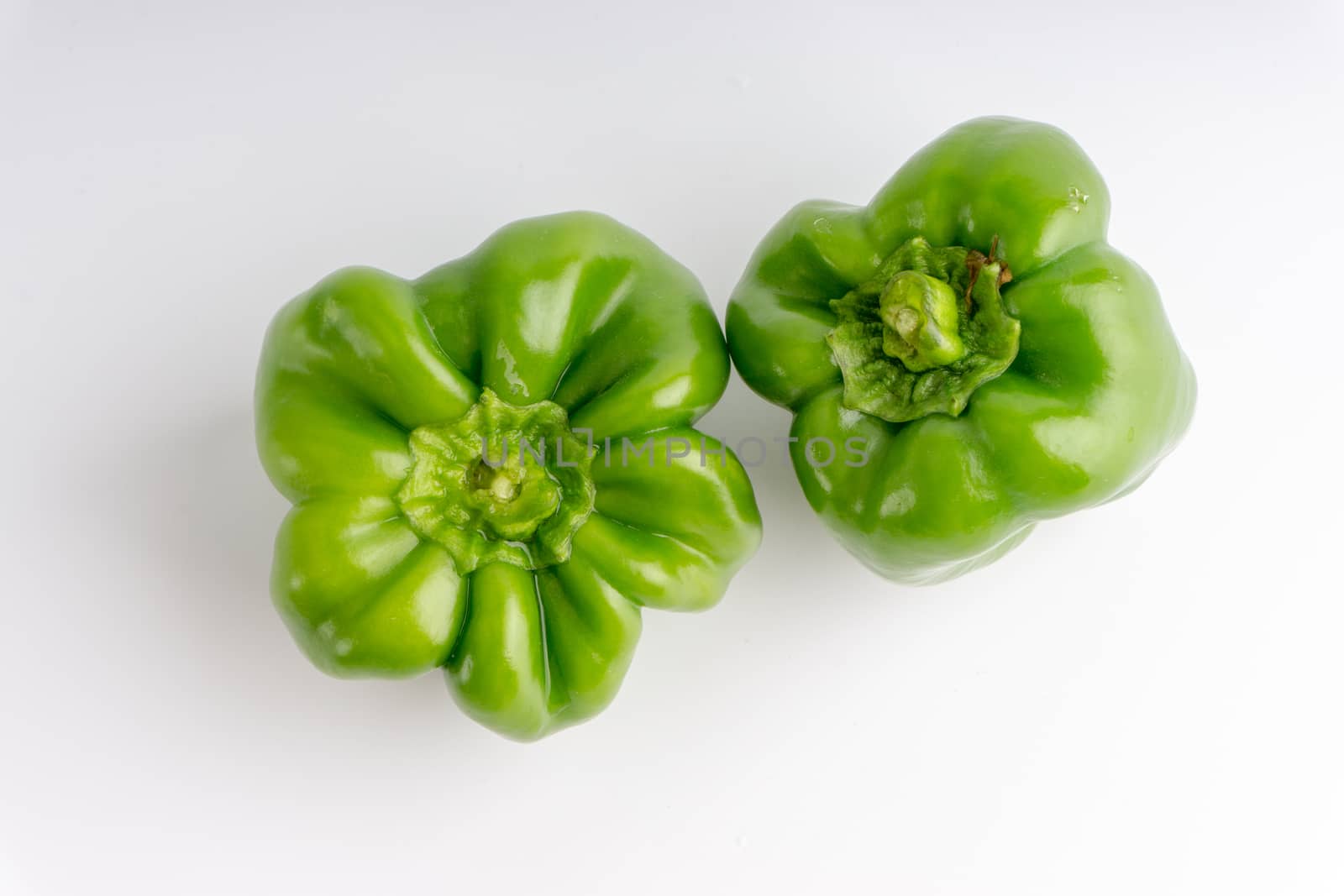 Fresh green bell peppers (capsicum) on a white background. Selective focus and crop fragment