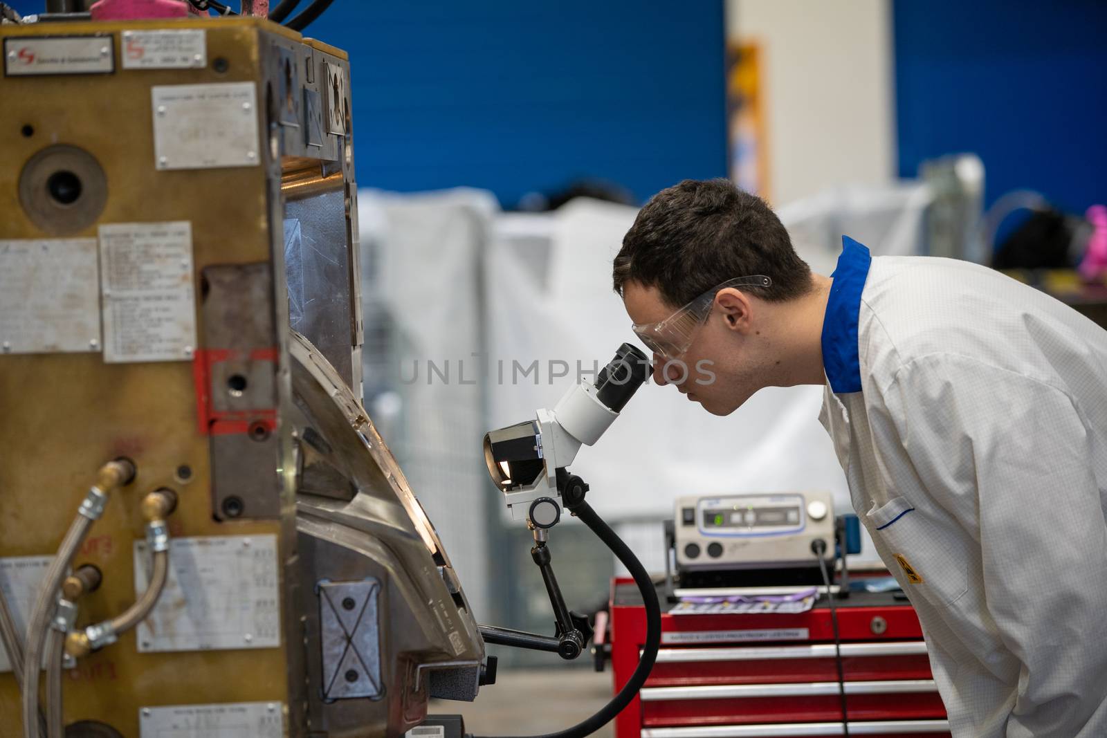 the engineer checks the correct setting of the metal mold for castings in the factory using a microscope.