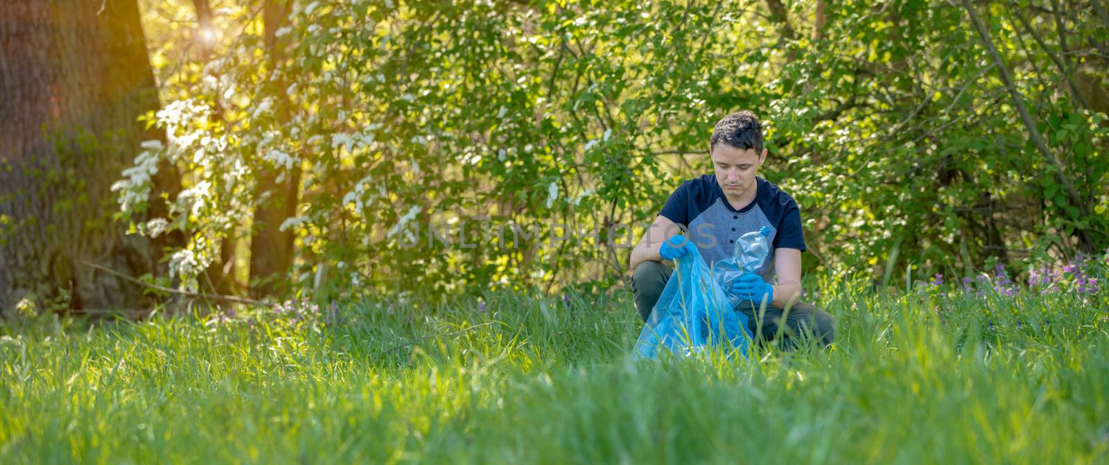 The volunteer cleans the forest from garbage, protects the environment.